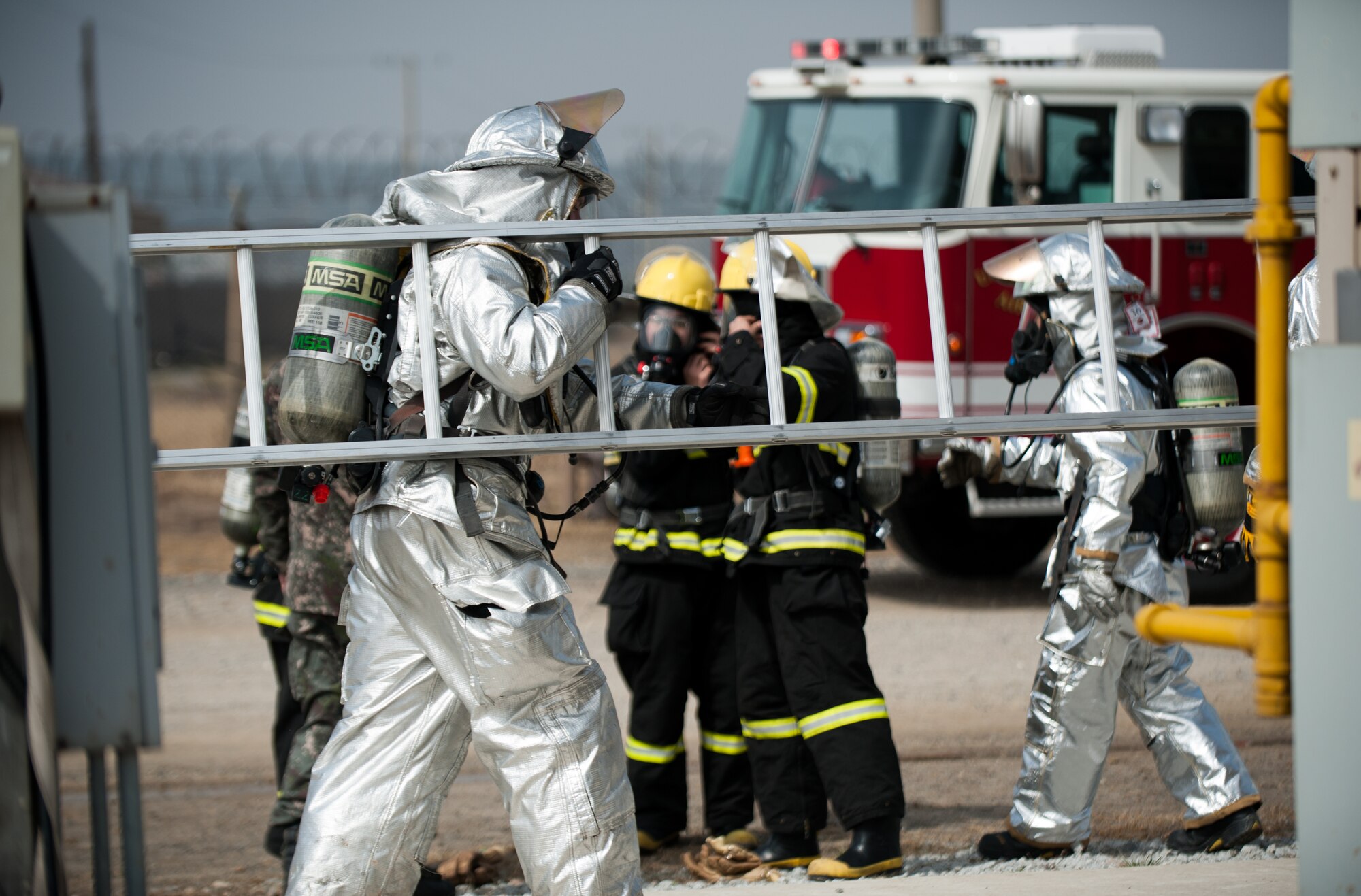 An 8th Civil Engineer Squadron firefighter transports a ladder while responding to a simulated fire at Kunsan Air Base, Republic of Korea, Mar. 18, 2014. The firefighters conducted classroom and live-fire training with firefighters from Marine Wing Support Squadron 172 and the Republic of Korea air force 38th Fighter Group fire department to enhance teamwork between fire departments. (U.S. Air Force photo by Staff Sgt. Clayton Lenhardt/Released)
