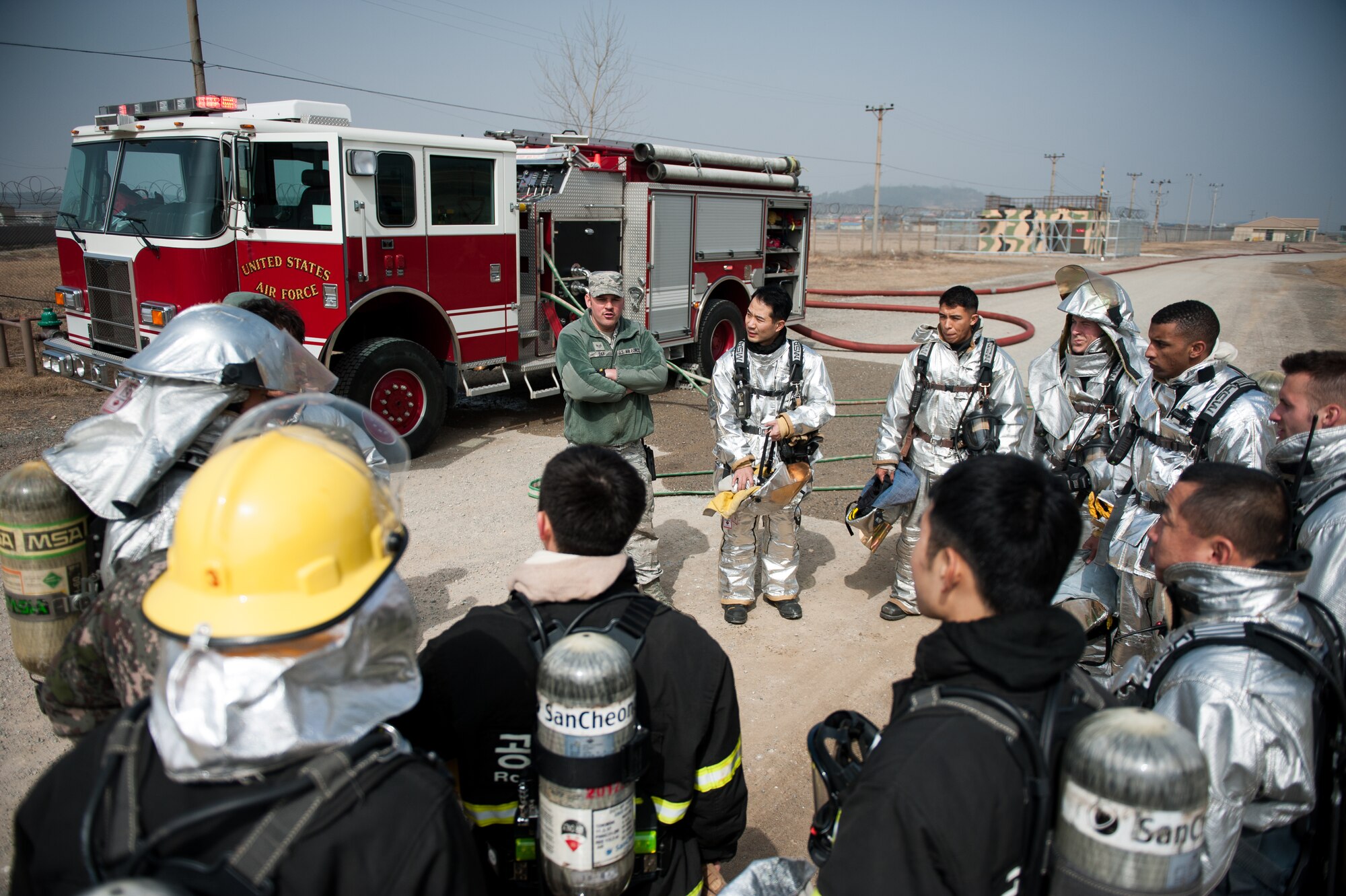 Staff Sgt. Ryan Day, 8th Civil Engineer Squadron firefighter, briefs 8th CES firefighters and Republic of Korea air force 38th Fighter Group firefighters after a training scenario at Kunsan Air Base, Republic of Korea, Mar. 18, 2014. The firefighters conducted classroom and live-fire training with firefighters from Marine Wing Support Squadron 172 fire department to enhance teamwork between fire departments. (U.S. Air Force photo by Staff Sgt. Clayton Lenhardt/Released)