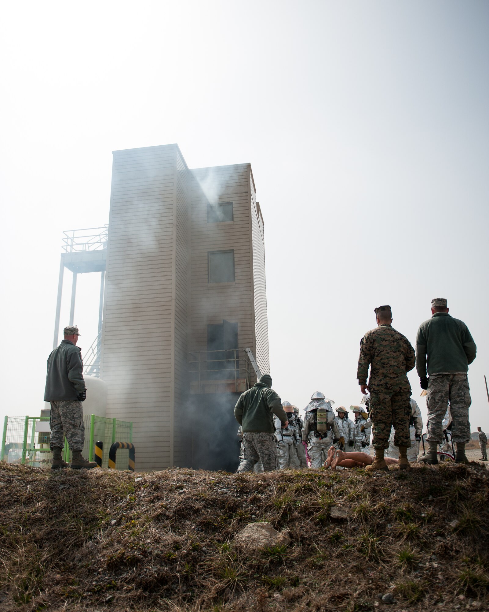 Evaluators observe as firefighters from the 8th Civil Engineer Squadron fire department and Marine Wing Support Squadron 172 respond to a simulated fire at Kunsan Air Base, Republic of Korea, Mar. 18, 2014. The firefighters conducted classroom and live-fire training with firefighters from Marine Wing Support Squadron 172 and the Republic of Korea air force 38th Fighter Group fire department to enhance teamwork between fire departments. (U.S. Air Force photo by Staff Sgt. Clayton Lenhardt/Released) 