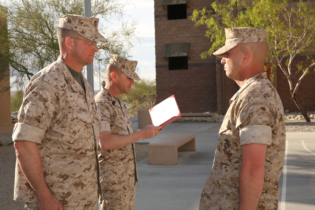 Lt. Col. Jeff Kenney, commanding officer, 3rd Battalion, 4th Marines, 7th Marine Regiment, prepares to award 1st. Sgt. Jack L. Shumate, company first sergeant, I Co., 3/4, a Navy and Marine Corps Commendation Medal with combat “V” for valor device as Sgt. Maj. Michael Miller, sergeant major, 3/4, reads the citation at their bachelors’ enlisted quarters’ courtyard, March 13, 2014.