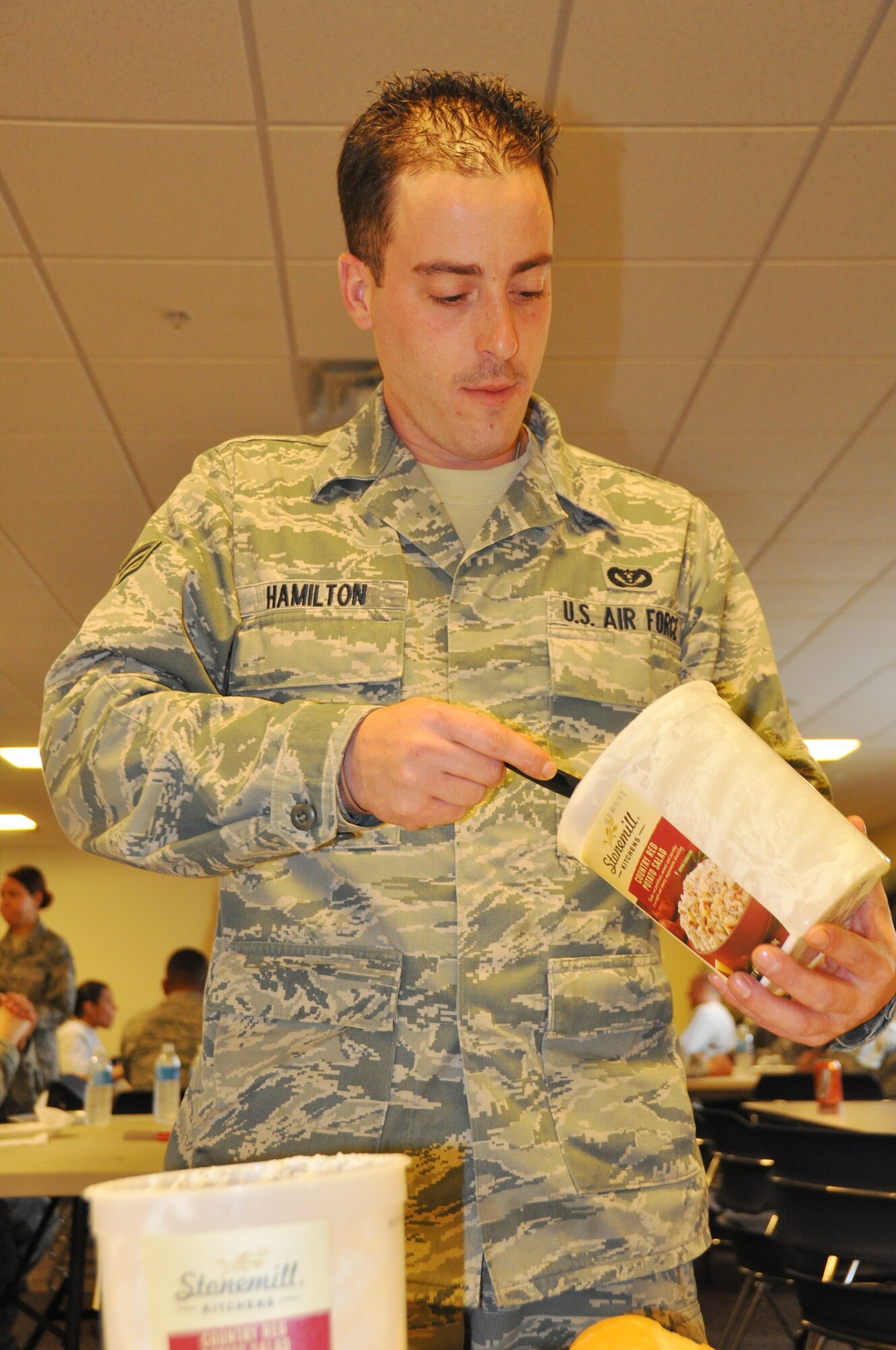 Senior Airman Robert Hamilton, 514th Civil Engineering Squadron member, adds potato salad to prepare his plate at the squadron’s Super Sandwich Saturday event held here March 22. The event was sponsored by the squadron's morale, welfare and recreation council in which members were treated to sausage and pepper subs, meatball subs, ice cream, music and card games (U.S. Air Force photo/Senior Airman Chelsea Smith).