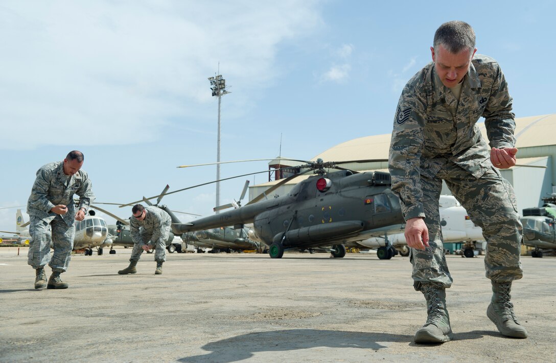 U.S. Air Force airmen perform a foreign object debris walk on the flight line at Luanda Air Base, Angola, before the arrival of a C-130J Super Hercules March 22, 2014. The airmen are participating in African Partnership Flight with the Angolan and Zambian air forces, an event which provides a collaborative learning environment for the airmen. (U.S. Air Force photo/Tech. Sgt. Benjamin Wilson)