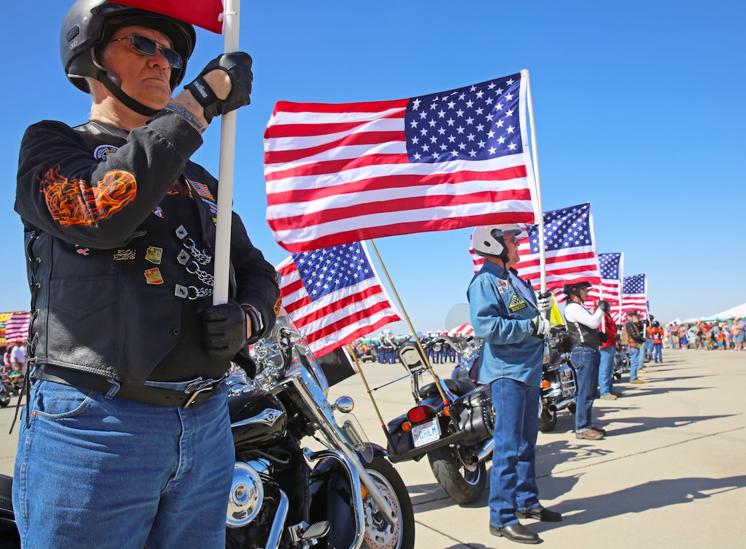 Larry Buthmann, a former service member and a native of Estherville, Iowa, (left), holds an American flag firmly as part of the Patriot Guard Riders opening ceremony for the 52nd Annual Yuma Airshow at Marine Corps Air Station Yuma, Ariz., March 15. The non-profit veterans support organization filed out on motorcycles and presented a flag line in honor of fallen veterans and active-duty service members.