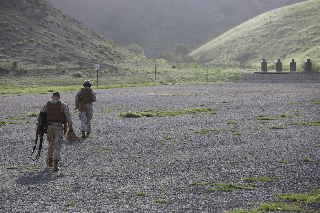 Two Marines with 1st Intelligence Battalion walk across a range during firearm training aboard Camp Pendleton, Calif., March 19. This training is an annual training requirement to ensure Marines are able to engage their targets in an urban environment.