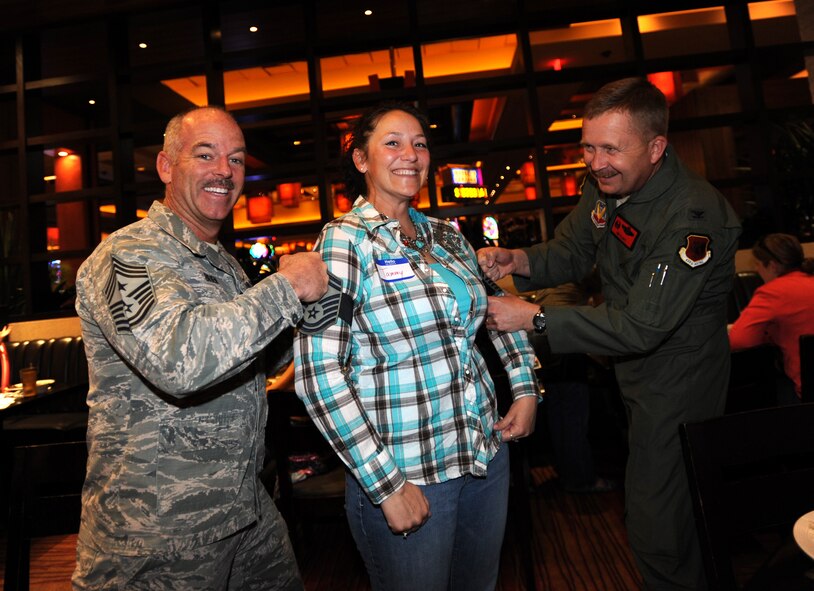 Chief Master Sgt. Butch Brien, left, 432nd Wing/432nd Air Expeditionary Wing command chief, and Col. James Cluff, 432nd Wing/432nd AEW commander, tack senior master sergeant stripes onto Tammy, wife of Master Sgt. Jody, 432nd Aircraft Maintenance Squadron assistant aircraft maintenance unit superintendent,  during a deployed family dinner at the Aliante Hotel in Las Vegas, Nev. Leadership from the 432nd Wing traveled to the homes of Creech Air Force Base’s selectees to personally congratulate them and their families on their selection for promotion. (U.S. Air Force photo by Senior Master Sgt. C.R.)