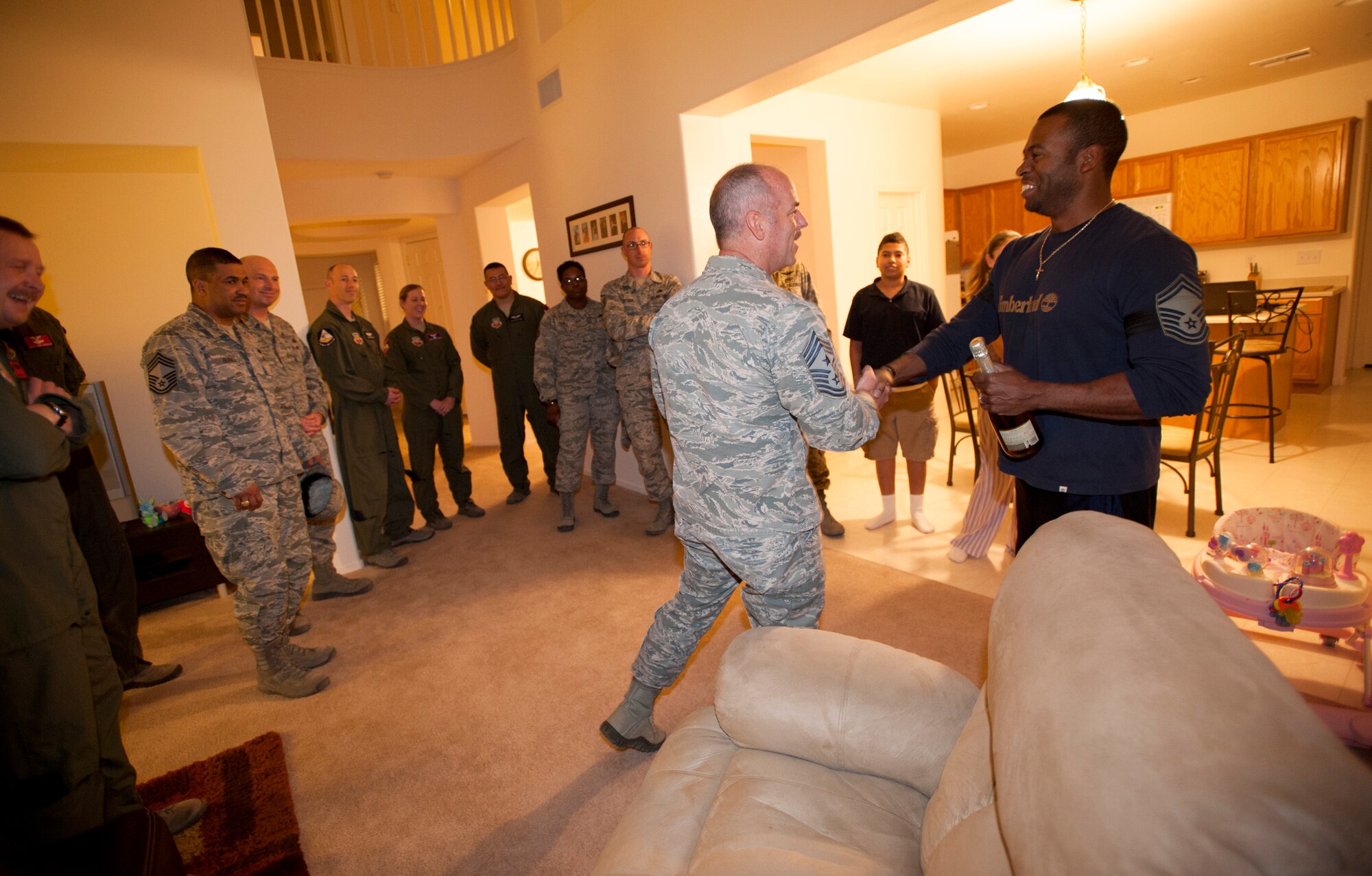 Chief Master Sgt. Butch Brien, 432nd Wing/432nd Air Expeditionary Wing command chief, congratulates Master Sgt. Darnell, 432nd Operations Support Squadron, on his selection to senior master sergeant after being surprised by leadership from the 432nd Wing/432nd AEW at his home. Darnell recently arrived at Creech Air Force Base, Nev., and was touched by the leadership’s efforts to make him and his family feel like a part of Team Creech. (U.S. Air Force photo by Senior Master Sgt. C.R.)