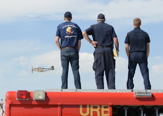Member of the L.A. County Fire Department's Urban Search and Rescue Team stand atop their emergency response vehicle watching a reenactment of a World War II dogfight between a P-51C Mustang (pictured) and enemy aircraft. World War II planes on display also included at F4U-1 Corsair and YAK-3. (U.S. Air Force photo by Kenji Thuloweit)
