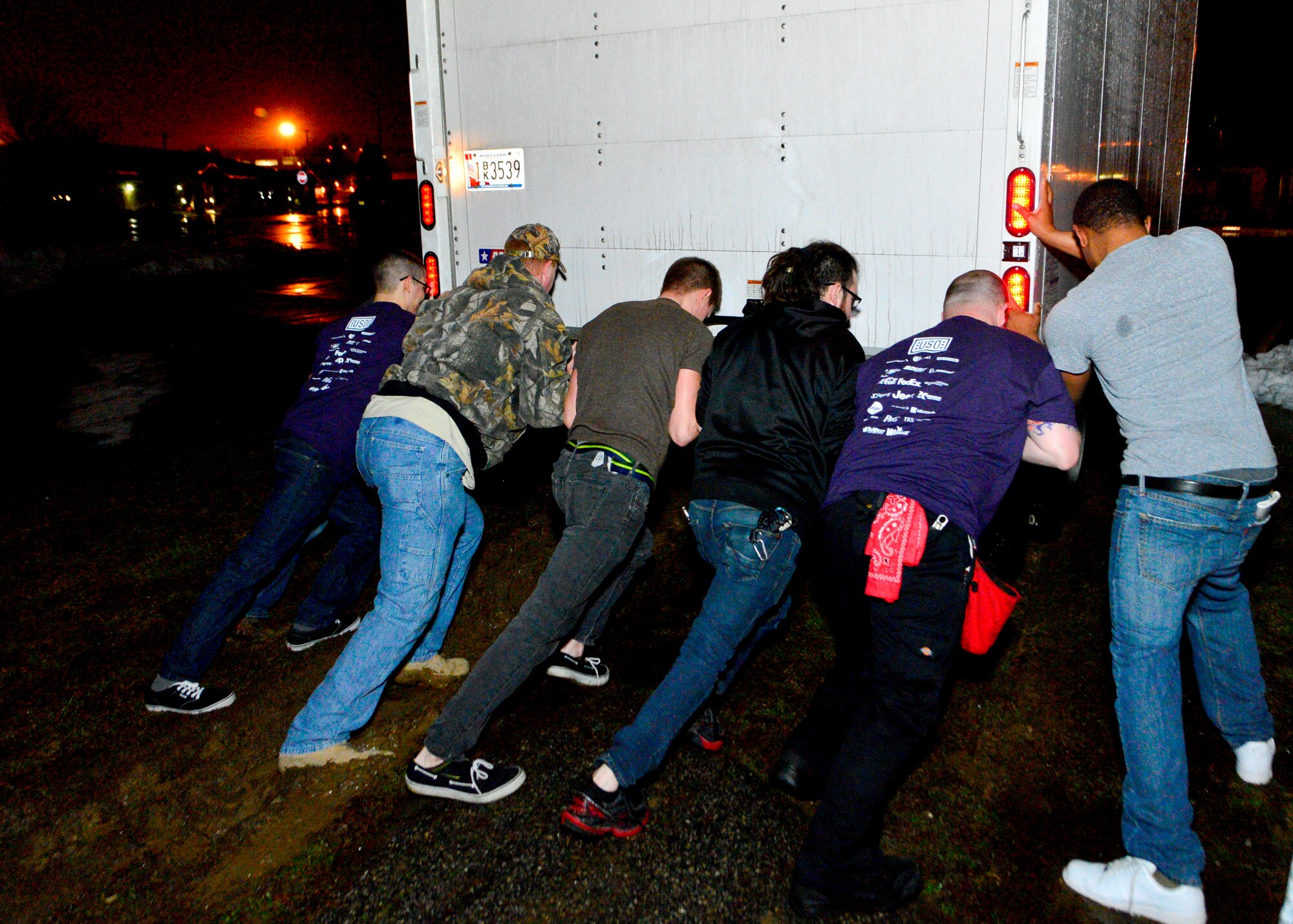 Team Dover Airmen and professional roadies attempt to push a box truck out of the mud during the teardown of the lighting, sound, and musical equipment March 19, 2014, at the base theater on Dover Air Force Base, Del. This truck was used to transport the concert equipment to and from the theater. (U.S. Air Force photo/Airman 1st Class Zachary Cacicia) 