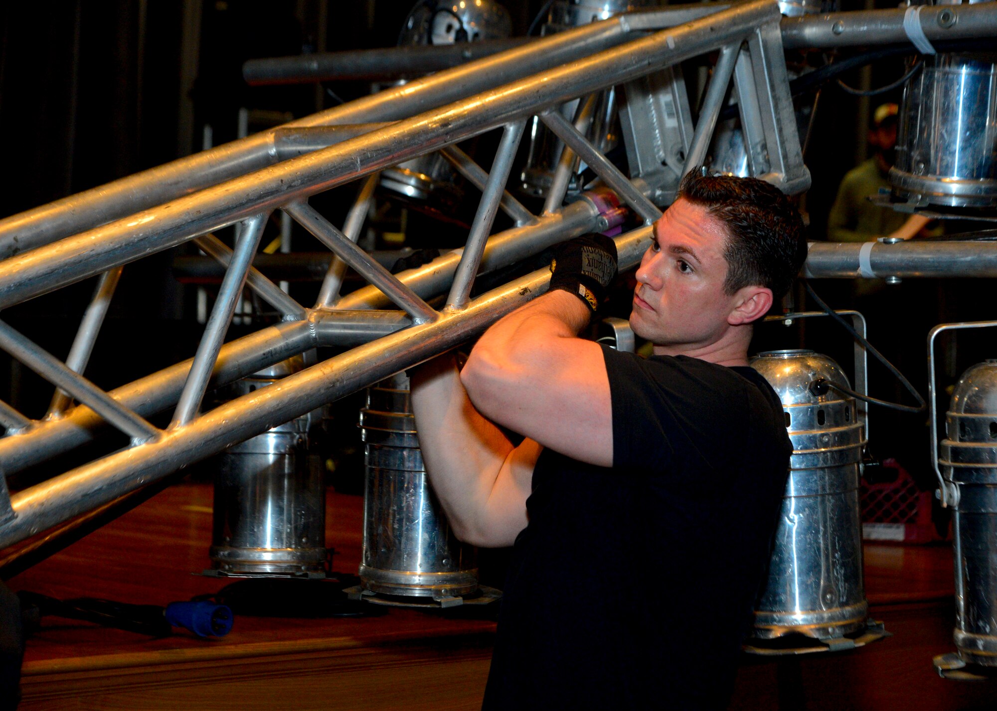 Staff Sgt. Zach Sielaff, 436th Civil Engineer Squadron firefighter, holds up a light truss during the teardown of the lighting, sound, and musical equipment March 19, 2014, inside the base theater on Dover Air Force Base, Del. This light truss was one of two constructed to hold lights for the concert. (U.S. Air Force photo/Airman 1st Class Zachary Cacicia)