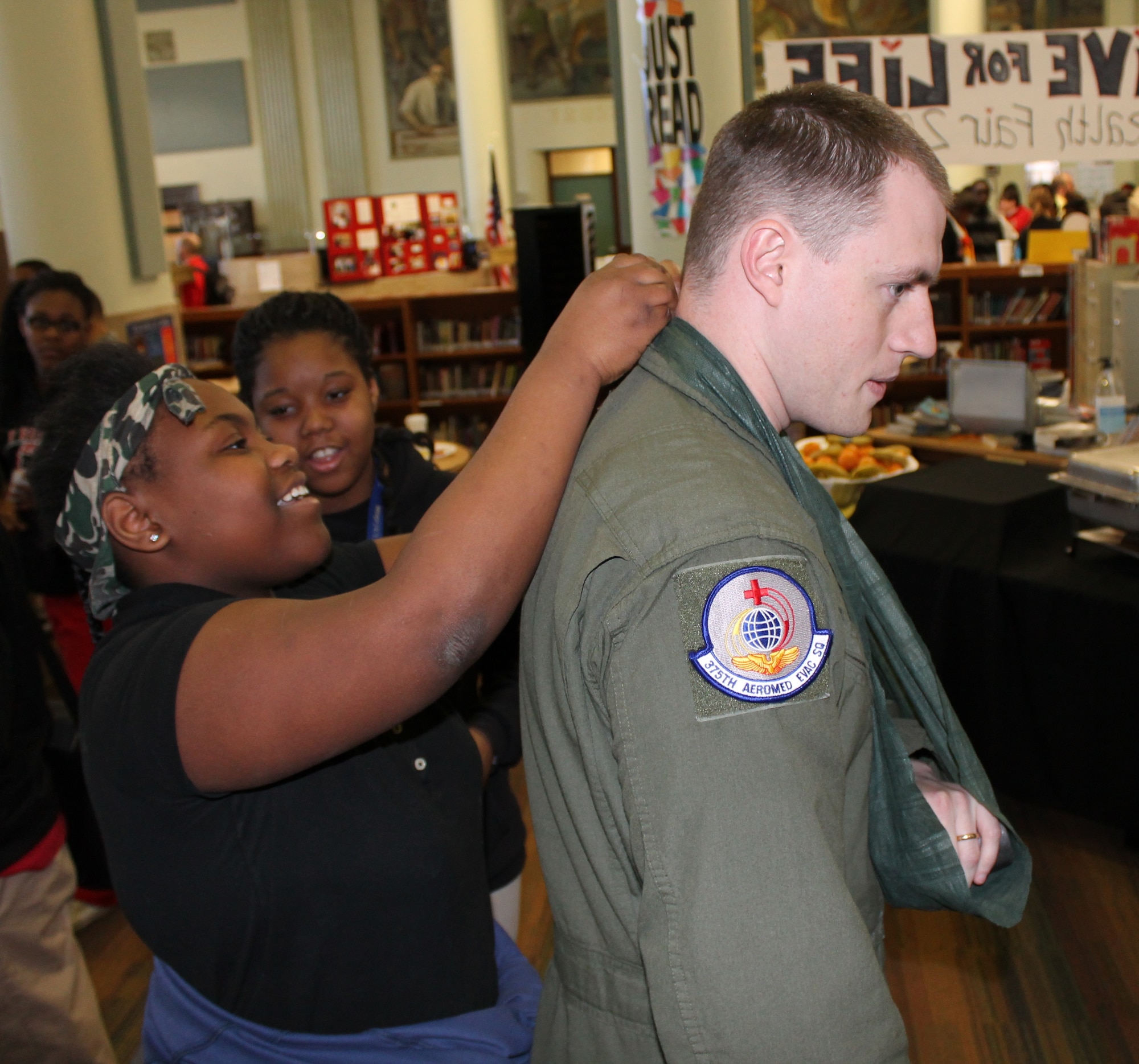 Kayla, a Lift for Life Academy seventh-grade student, ties a sling on Staff Sgt. Greyson Thompson, 375th Aerial Evacuation Squadron Aerial Evacuation technician, at the Self Aid Buddy Care station in the school’s health fair, Feb. 26, 2014. Service members from Scott Air Force Base, Ill., manned information stations, talked about fitness, discussed resiliency and demonstrated Self Aid Buddy Care techniques to the students. (Courtesy photo/Katelyn Hippen-Smith)