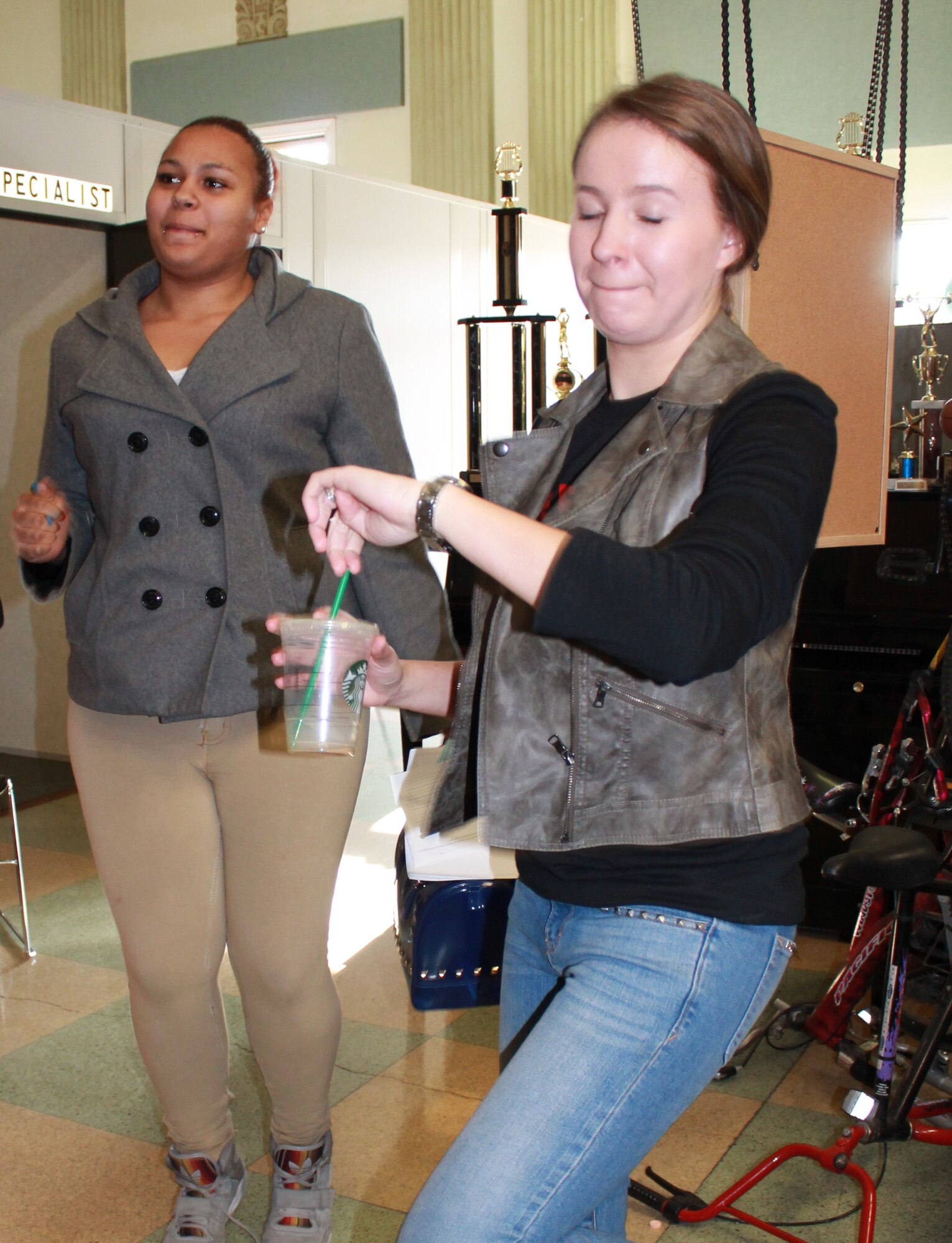 Jessica Roemelt, a Goldfarb School of Nursing at Barnes-Jewish College nursing student, checks her watch as she leads Mishayla, a Lift for Life Academy 12th-grade student, as they jog in place for 30 seconds and then continue to jog for another 30 seconds while breathing through a straw to demonstrate the symptoms of emphysema. Nursing school students partnered with service members from Scott Air Force Base, Ill, to man information stations at a St. Louis charter school health fair, Feb. 26, 2014. (Courtesy photo/Katelyn Hippen-Smith)