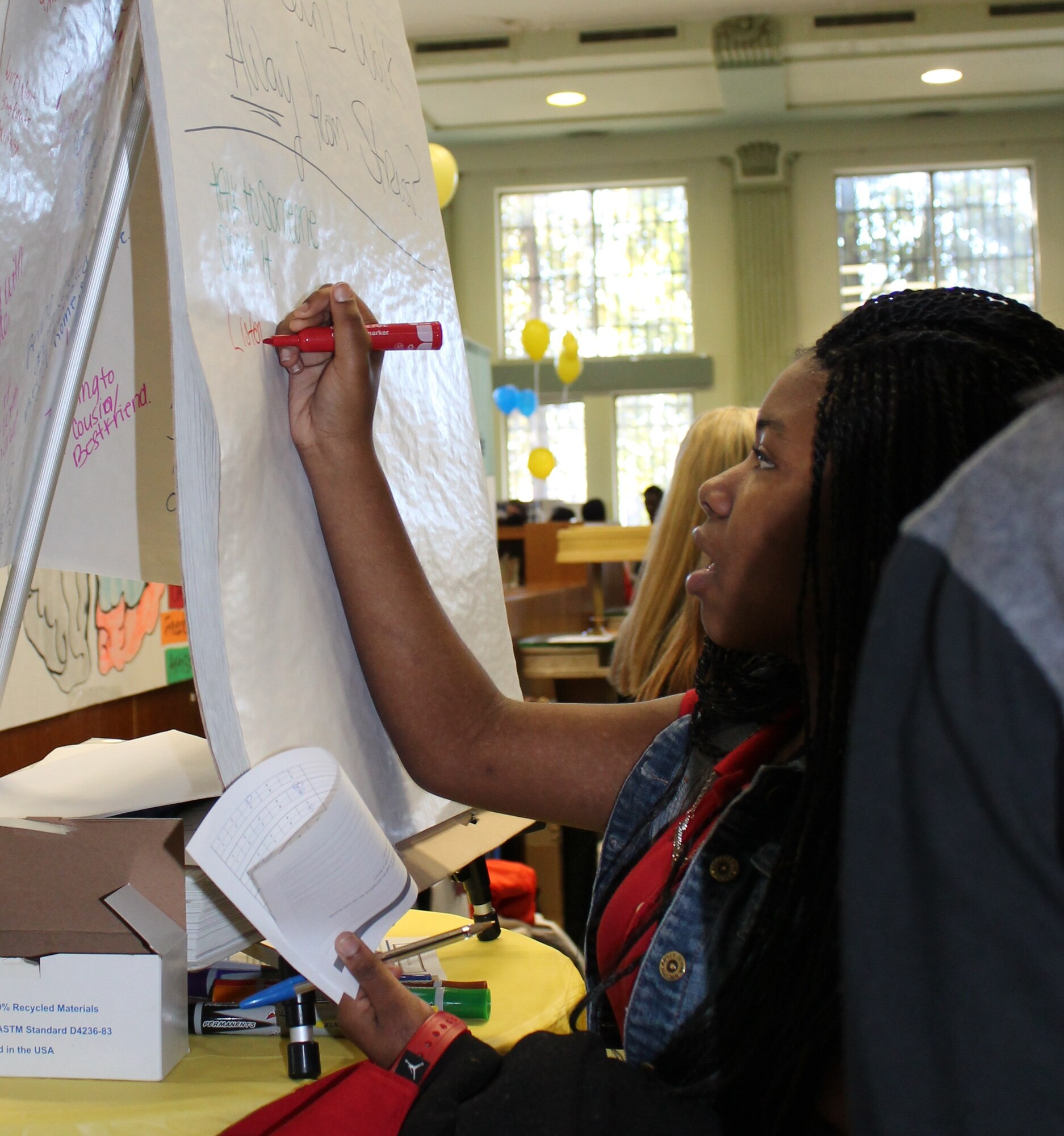 Makala, a Lift for Life Academy sixth-grade student, writes her stressors on the stress board, Feb. 26, 2014, during a health fair at the school. Service members from Scott Air Force Base, Ill., manned information stations, talked about fitness, discussed resiliency and demonstrated Self Aid Buddy Care techniques to the students. (Courtesy photo/Katelyn Hippen-Smith)