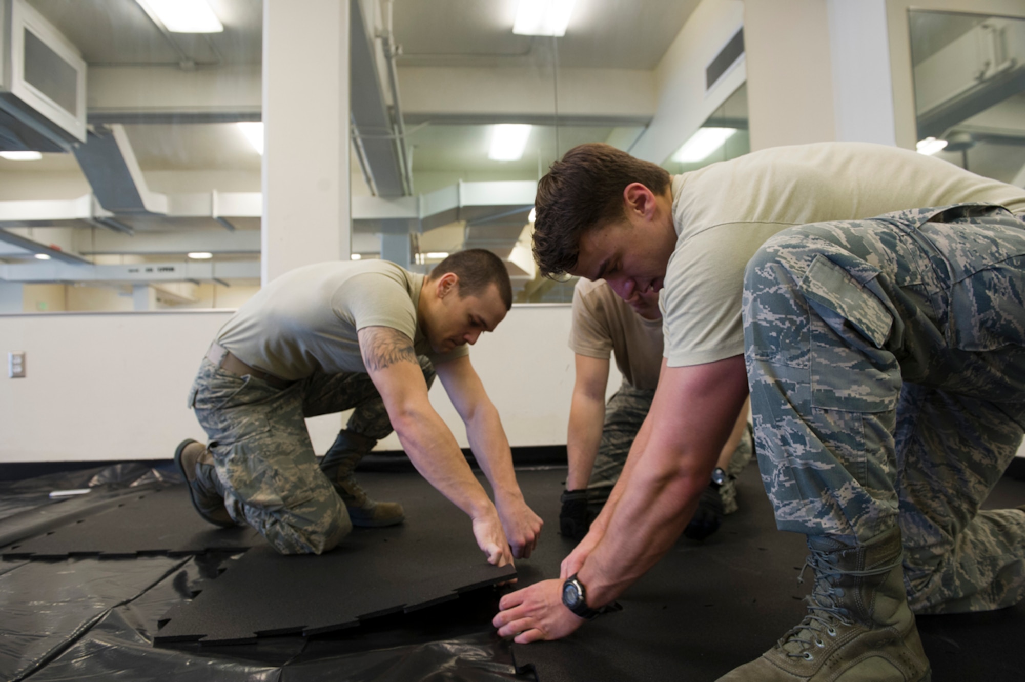 Airman 1st Class Cody Brant, 673d Contracting Squadron, Senior Airman Jacob Revell, 517th Air Support Squadron, and Senior Airman Tyler Denslow, 3rd Munitions Squadron, lay down mats in the aerobics room of the Elmendorf Fitness Center on Joint Base Elmendorf Richardson, Alaska, March 17, 2014.  Due to the gym being used as lodging, the fitness center will have reduced hours and the Hangar 5 field house will be closed. (U.S. Air Force photo/Airman 1st Class Omari Bernard)