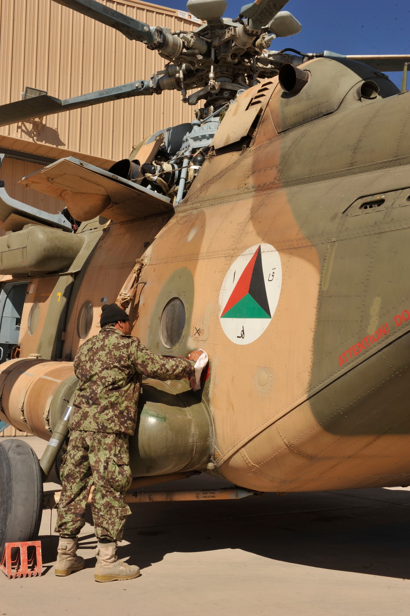 An Afghan aviation maintenance student wipes fluid after checking their levels while performing maintenance on an Mi-17 helicopter at Shindand Airfield, Afghanistan, March 10, 2014. U.S. military advisors are training Afghan military members to fly and maintain aircraft at Shindand.(U.S. Air Force photo by Senior Master Sgt. Gary J. Rihn/Released)