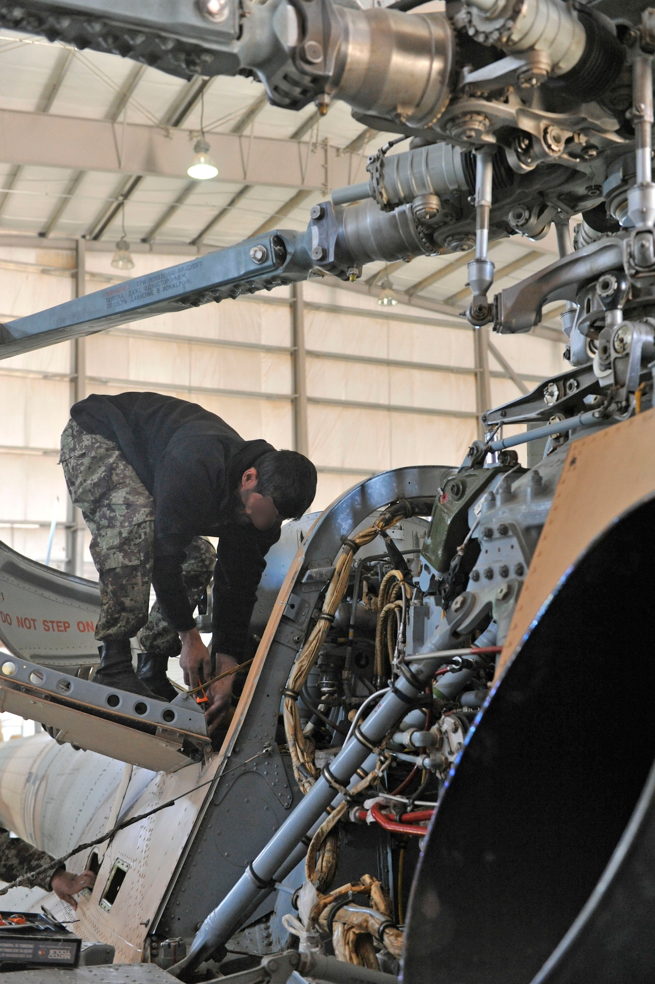 An Afghan aviation maintenance student performs maintenance on an Mi-17 helicopter at Shindand Airfield, Afghanistan, March 10, 2014. U.S. military advisors are training Afghan military members to fly and maintain aircraft at Shindand.(U.S. Air Force photo by Senior Master Sgt. Gary J. Rihn/Released)( Faces blurred for security purposes)