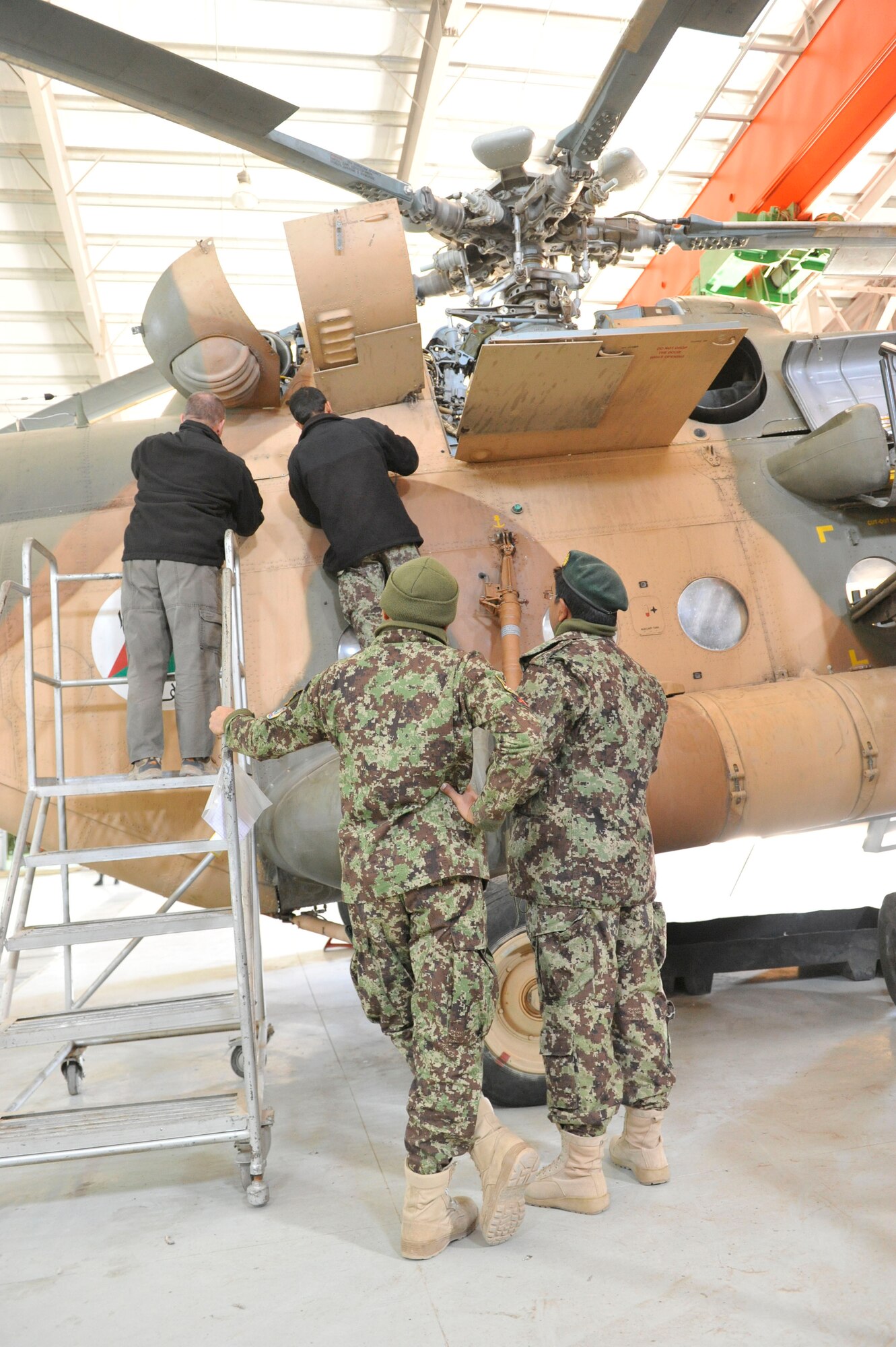Two Afghan aviation maintenance students perform maintenance on an Mi-17 helicopter under the supervision of two crew chiefs at Shindand Airfield, Afghanistan, March 10, 2014. U.S. military advisors are training Afghan military members to fly and maintain aircraft at Shindand.(U.S. Air Force photo by Senior Master Sgt. Gary J. Rihn/Released)