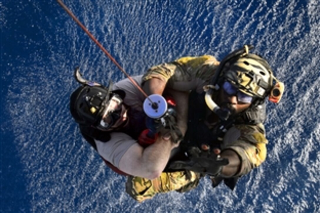 A U.S. Air Force pararescueman assists U.S. Air Force Chief Master Sgt. Gerald Barnett, left, via hoist into a HH-60 Pave Hawk helicopter as part of a water rescue exercise near Camp Lemonnier, Djibouti, March 20, 2014. Barnett, senior enlisted adviser, is assigned to the 449th Air Expeditionary Group, and the pararescueman is assigned to the 82nd Expeditionary Rescue Squadron.