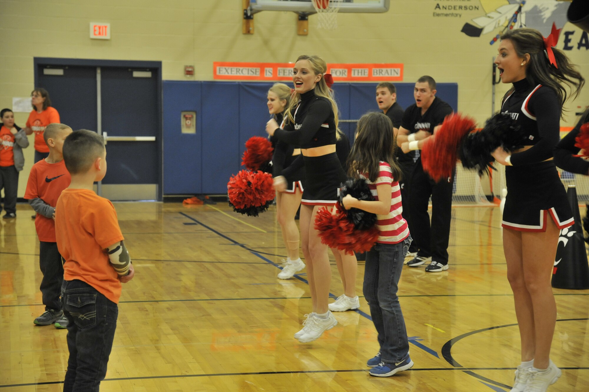 University of Cincinnati cheerleaders perform along with several students from Michael Anderson Elementary School at Fairchild Air Force Base, Wash., March 19, 2014. The cheerleaders, along with a pep band, came to Fairchild during their visit to Spokane, Wash. to perform around base in hopes to raise morale. (U.S. Air Force photo by Senior Airman Mary O'Dell/Released)