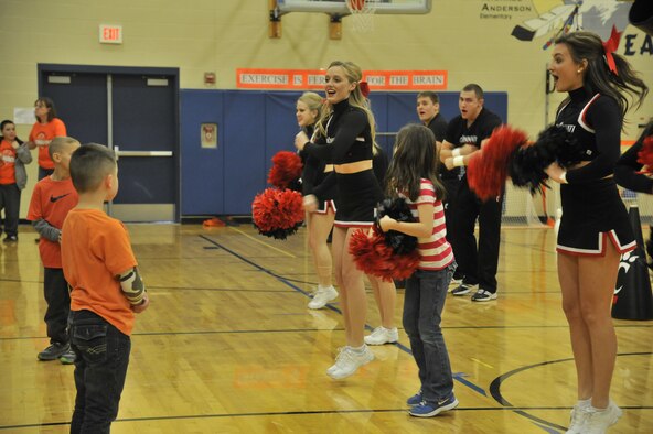 University of Cincinnati cheerleaders perform along with several students from Michael Anderson Elementary School at Fairchild Air Force Base, Wash., March 19, 2014. The cheerleaders, along with a pep band, came to Fairchild during their visit to Spokane, Wash. to perform around base in hopes to raise morale. (U.S. Air Force photo by Senior Airman Mary O'Dell/Released)