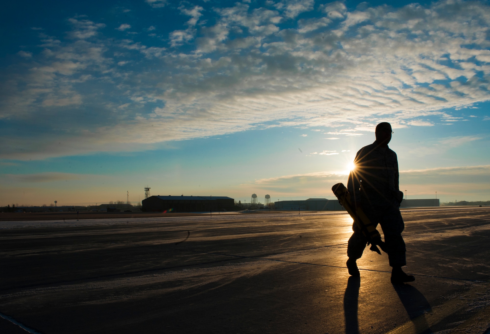 An Airman from the 5th Civil Engineer Squadron removes a Trimble Total Station from the flight line at Minot Air Force Base, N.D., March 19, 2014. The station was used to check the alignment of two Precision Approach Path Indicators and a snow fence which will act as temporary runway lighting and ending points during construction on the flight line later this year. (U.S. Air Force photo/Senior Airman Stephanie Sauberan)