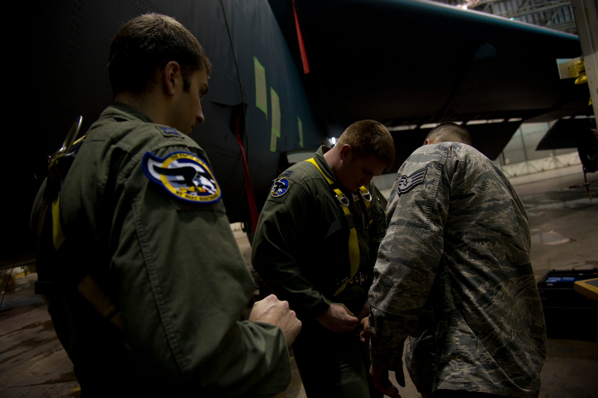 Staff Sgt. John M. Silva, 5th Aircraft Maintenance Squadron dedicated crew chief, puts harnesses on 69th Bomb Squadron pilots Capt. Joseph Cangealose and Capt. Britt Nemeth after an aircraft wash at Minot Air Force Base, N.D., Jan. 10, 2014. Silva promotes a strong working relationship between the two crews by including the air crew in maintenance shop functions. (U.S. Air Force photo/Senior Airman Brittany Y. Auld)