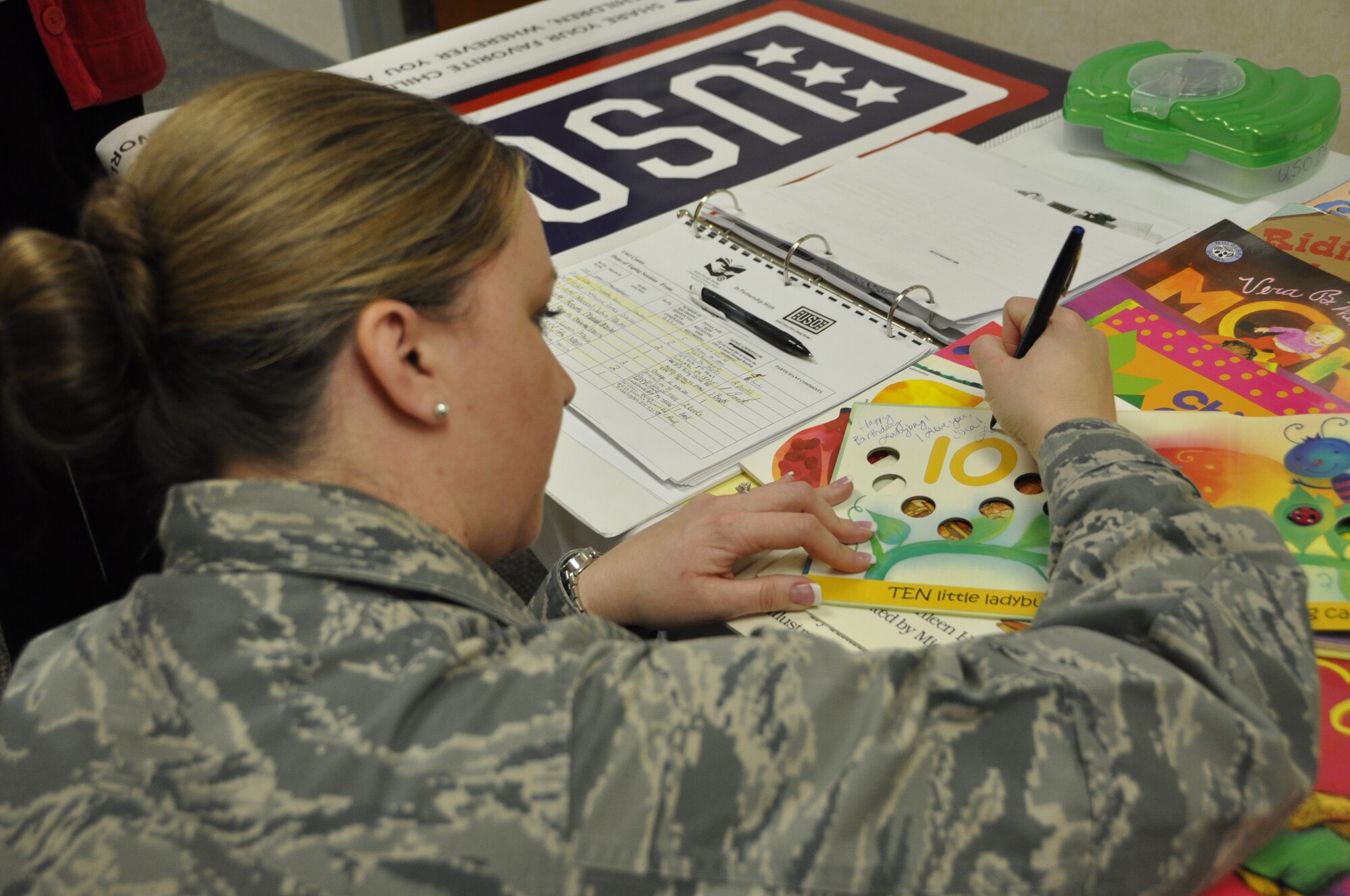 Air Force Maj. Jennifer M. Piggott, Public Affairs Officer, signs a book she plans to read to her daughter during the USO Read Around the World event at Air Force Mortuary Affairs Operations, Dover Air Force Base, Del., March 25, 2014.  Piggott is deployed to the Mortuary from Joint Force Headquarters, Massachusetts Air National Guard, Hanscom AFB, Mass.  (U.S. Air Force photo/Staff Sgt. Chalanda Roberts)
