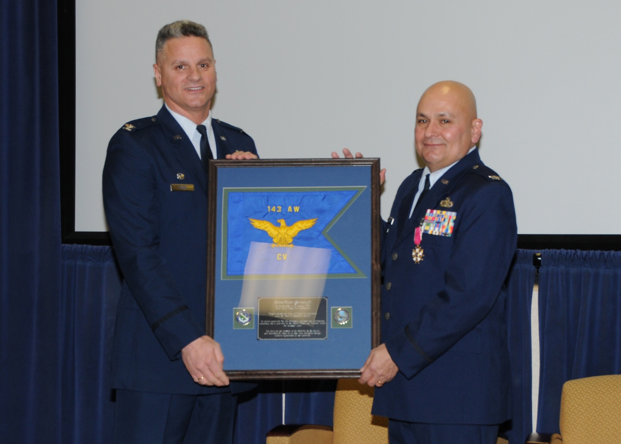 Colonel Arthur Floru (right), 143d Airlift Wing Commander, presents Colonel Robert Germani Jr. (left), outgoing 143d Airlift Wing Vice Commander witha replica of the 143d Airlift Wing Guidon upon his retirement after 34 years of dedicated service to the Rhode Island National Guard. National Guard Photo by Technical Sgt Jason Long (RELEASED)