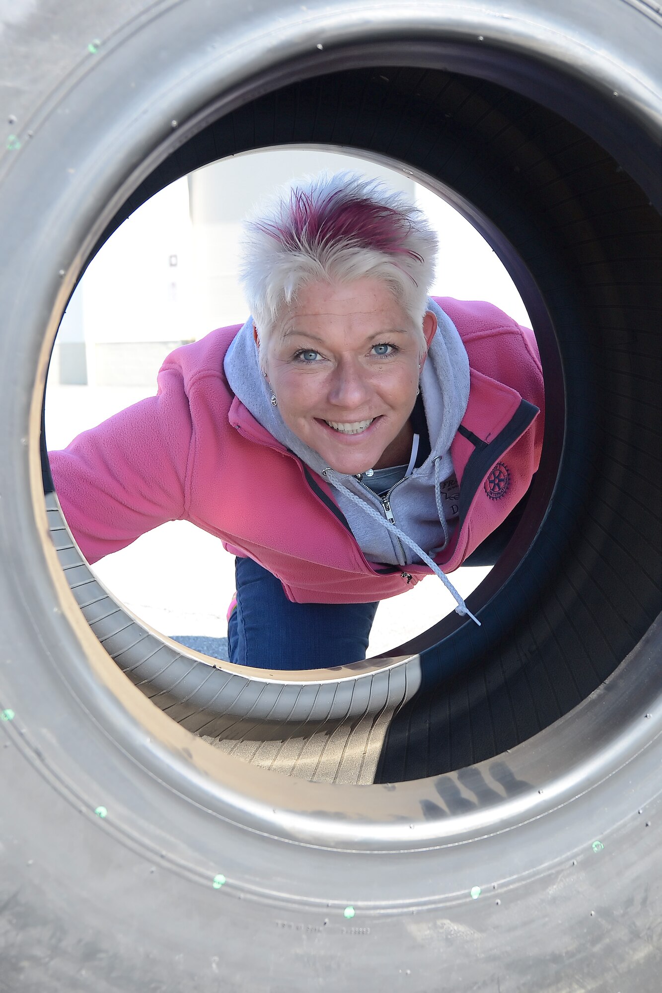 Dawn Nickerson-Banez, owner of the Frankfurt Bakery in Dover, Del., poses within the opening of an aircraft tire after winning a friendly tire-roll competition near the 436th Logistics Readiness Squadron, March 21, 2014, at Dover Air Force Base, Del. The tire-roll competition was done in relay format and challenged the competitors to work together to roll a large aircraft tire the length of a parking lot. (U.S. Air Force photo/Greg L. Davis)