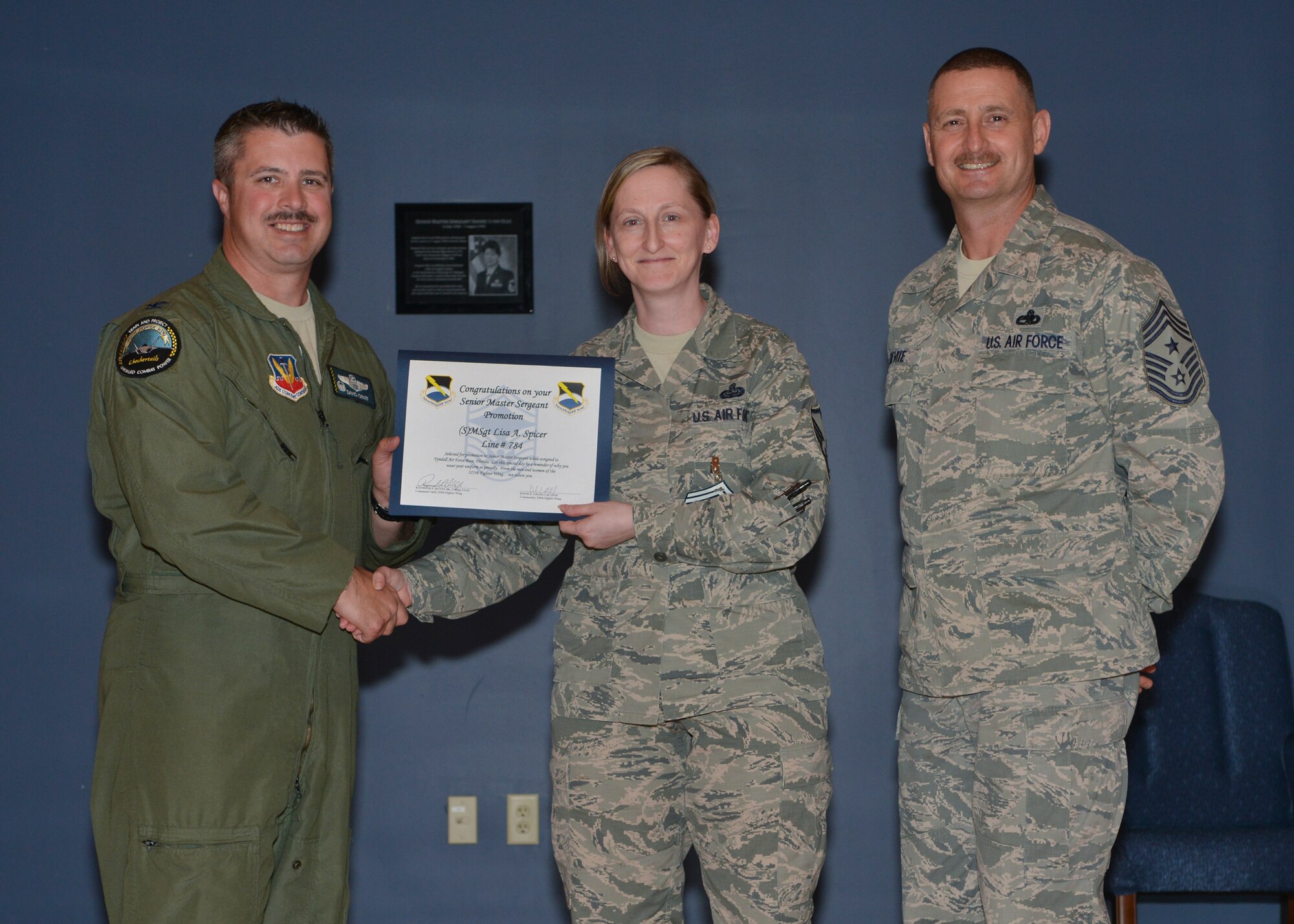 Col. David E. Graff, 325th Fighter Wing commander (left) and Chief Master Sgt. Raymond F. DeVite, 325th FW Command Chief Master Sergeant (far right), present Master Sgt.Lisa A. Spicer, 325th Communication Squadron (middle) with her senior master sergeant promotion line number certificate March 21 at the Horizons ballroom. Team Tyndall recognized nine senior master sergeants Sergeants promotes.  (U.S. Air Force photo by Staff Sgt. Javier Cruz)
