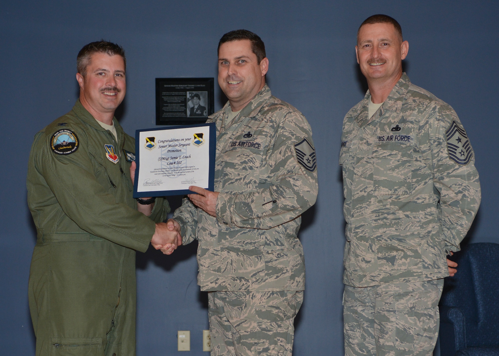 Col. David E. Graff, 325th Fighter Wing commander (left) and Chief Master Sgt. Raymond F. DeVite, 325th FW Command Chief Master Sergeant (far right), present Master Sgt.Jamie T. Leach, 325th Aircraft Maintenance Squadron (middle) with his senior master sergeant promotion line number certificate March 21 at the Horizons ballroom. Team Tyndall recognized nine senior master sergeants promotes.  (U.S. Air Force photo by Staff Sgt. Javier Cruz)