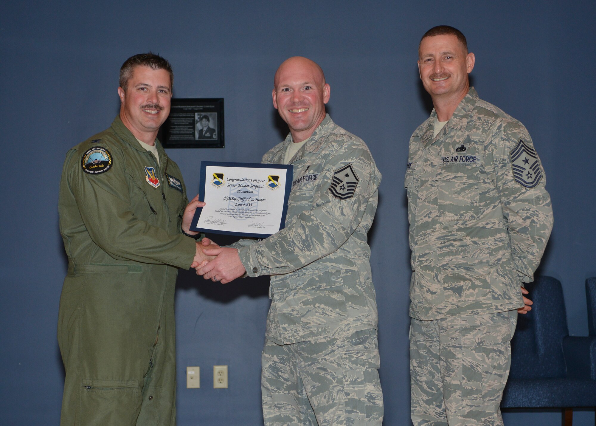 Col. David E. Graff, 325th Fighter Wing commander (left) and Chief Master Sgt. Raymond F. DeVite, 325th FW Command Chief Master Sergeant (far right), present Master Sgt.Clifford B. Hodge, 325th Aircraft Maintenance Squadron (middle) with his senior master sergeant promotion line number certificate March 21 at the Horizons ballroom. Team Tyndall recognized nine senior master sergeants promotes.  (U.S. Air Force photo by Staff Sgt. Javier Cruz)