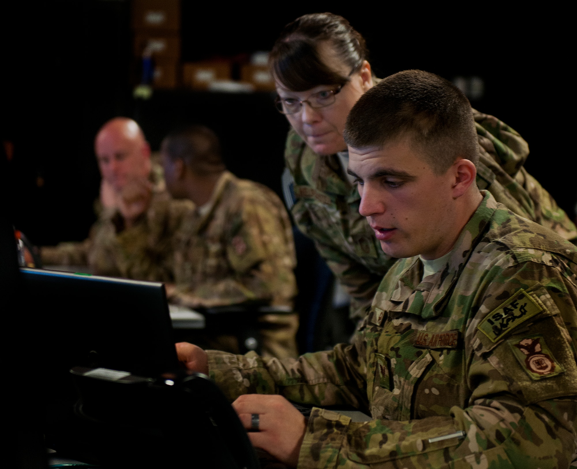 The battle captain and watch keeper converse during a Joint Defense Operations Center exercise at Eglin AFB, Fla., March 21. The exercise simulated real-world force protection conditions at Kandahar Air Field, Afghanistan, to help deployers have specific location training before arriving to their new assignment. The training was facilitated by the 96th Ground Combat Training Squadron. (U.S. Air Force photo/Samuel King Jr.)