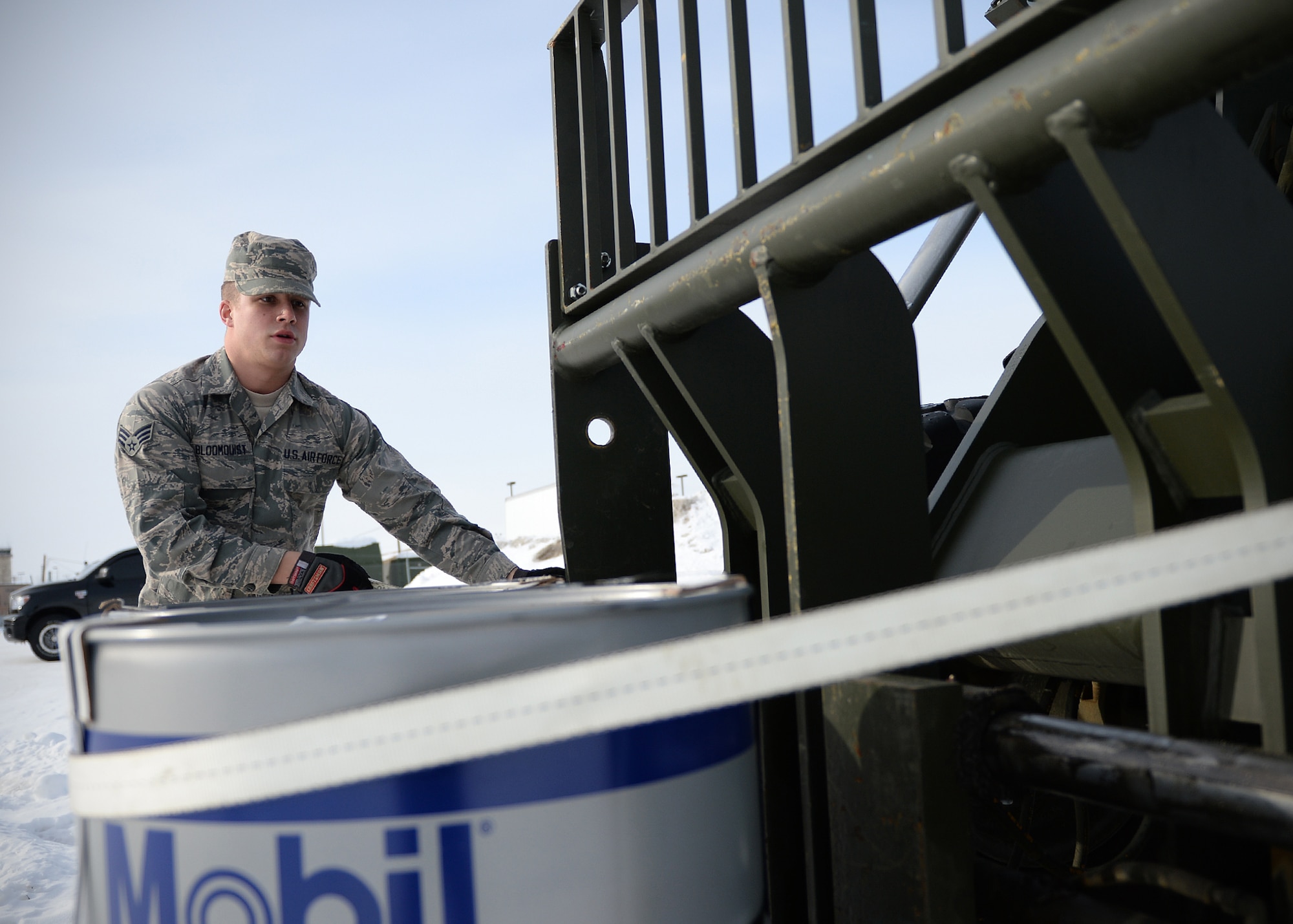 Senior Airman Gregory Bloomquist, 354th Logistic Readiness Squadron vehicle operator, straps oil barrels to a fork lift March 18, 2014 Eielson Air Force Base, Alaska. Vehicle operators provide many services such as moving equipment, transporting Airmen and shuttling distinguished visitors to Eielson. (U.S. Air Force photo by Staff Sgt. Shawn Nickel/Released)