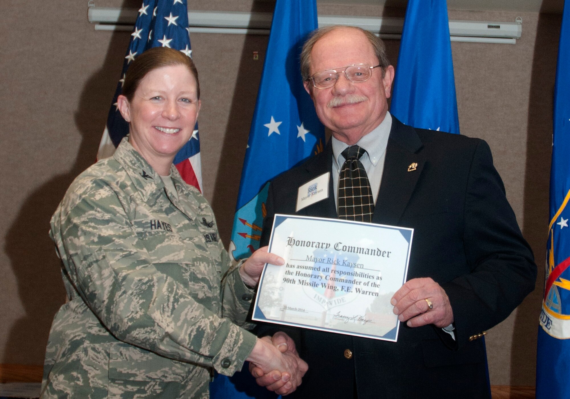 Col. Tracey Hayes, 90th Missile Wing commander, presents Cheyenne Mayor Rick Kaysen with an honorary commander certificate March 20, 2014, at the Trail’s End Club. This is Kaysen’s second time participating in the Honorary Commander Program. The program brings together members of the Cheyenne community and helps F.E. Warren commanders keep a pulse on the community concerns. The purpose of the Honorary Commanders Program is to increase public awareness and understanding of the Air Force and the mission, policies, programs and people of the F.E. Warren AFB. (U.S. Air Force photo by Airman Malcolm Mayfield)