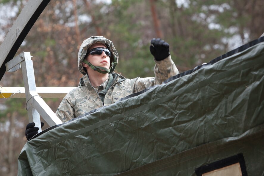 Senior Airman Andrew Bracken, 175th Civil Engineer Squadron, Maryland Air National Guard assists his team members in constructing a tent during a practical application portion of the Silver Flag exercise, March 24, 2014, Ramstein Air Base, Germany. The Silver Flag exercise simulates training relevant to building and beddown of a ba...re base operation in a deployed environment. (U.S. Air National Guard photo by Master Sgt. Gareth Buckland/Released