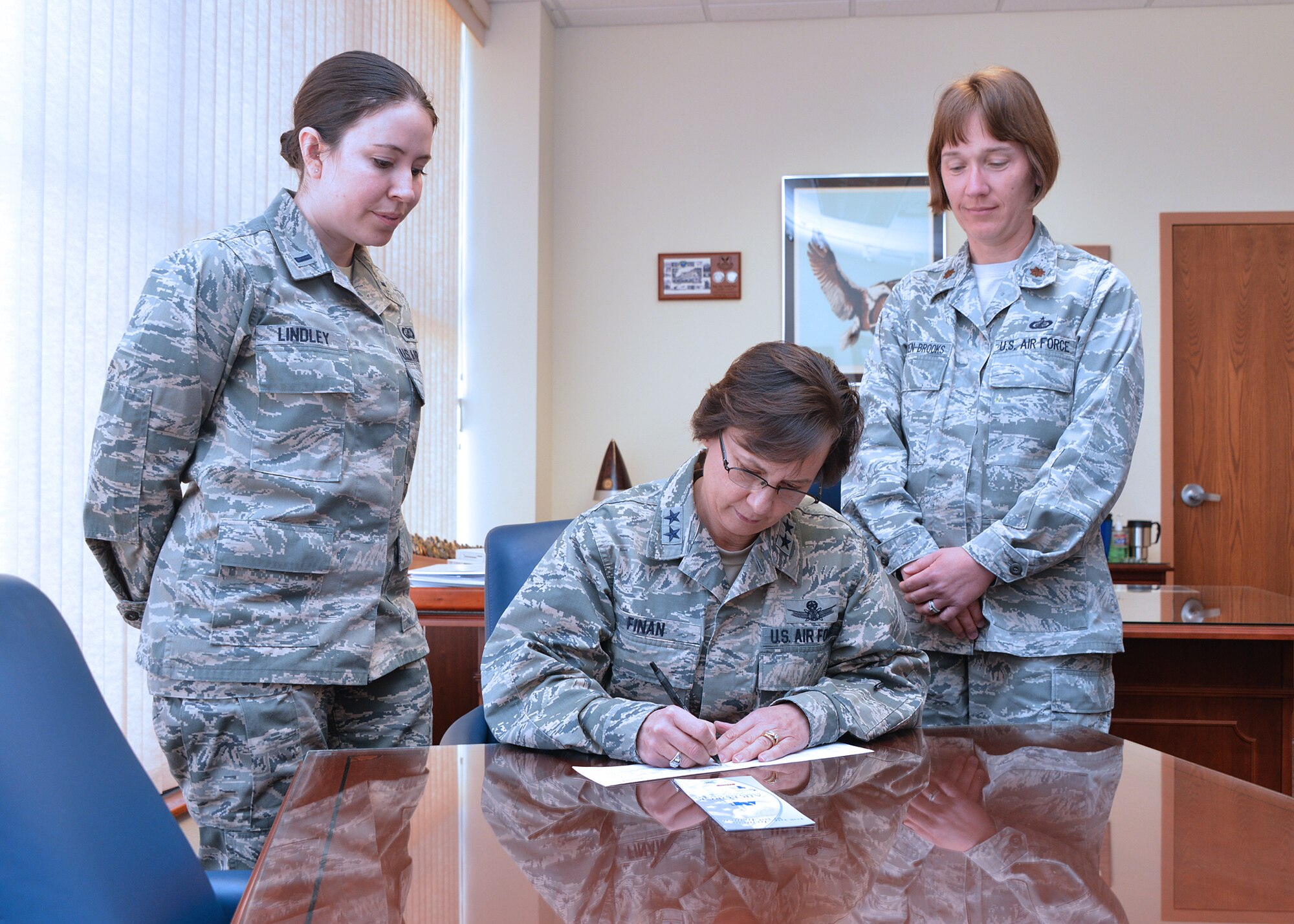 Maj. Gen. Sandra Finan, Air Force Nuclear Weapons Center commander, signs a pledge card for the Air Force Assistance Fund Campaign, with 1st Lt Drew Lindley, installation AFAF representative, and Maj. Sharon Chelgren-Brooks, AFNWC's representative. The campaign raises funds for the charitable affiliates that provide support to Air Force families in need.  It runs through April 11. (Photo by Todd Berenger)
