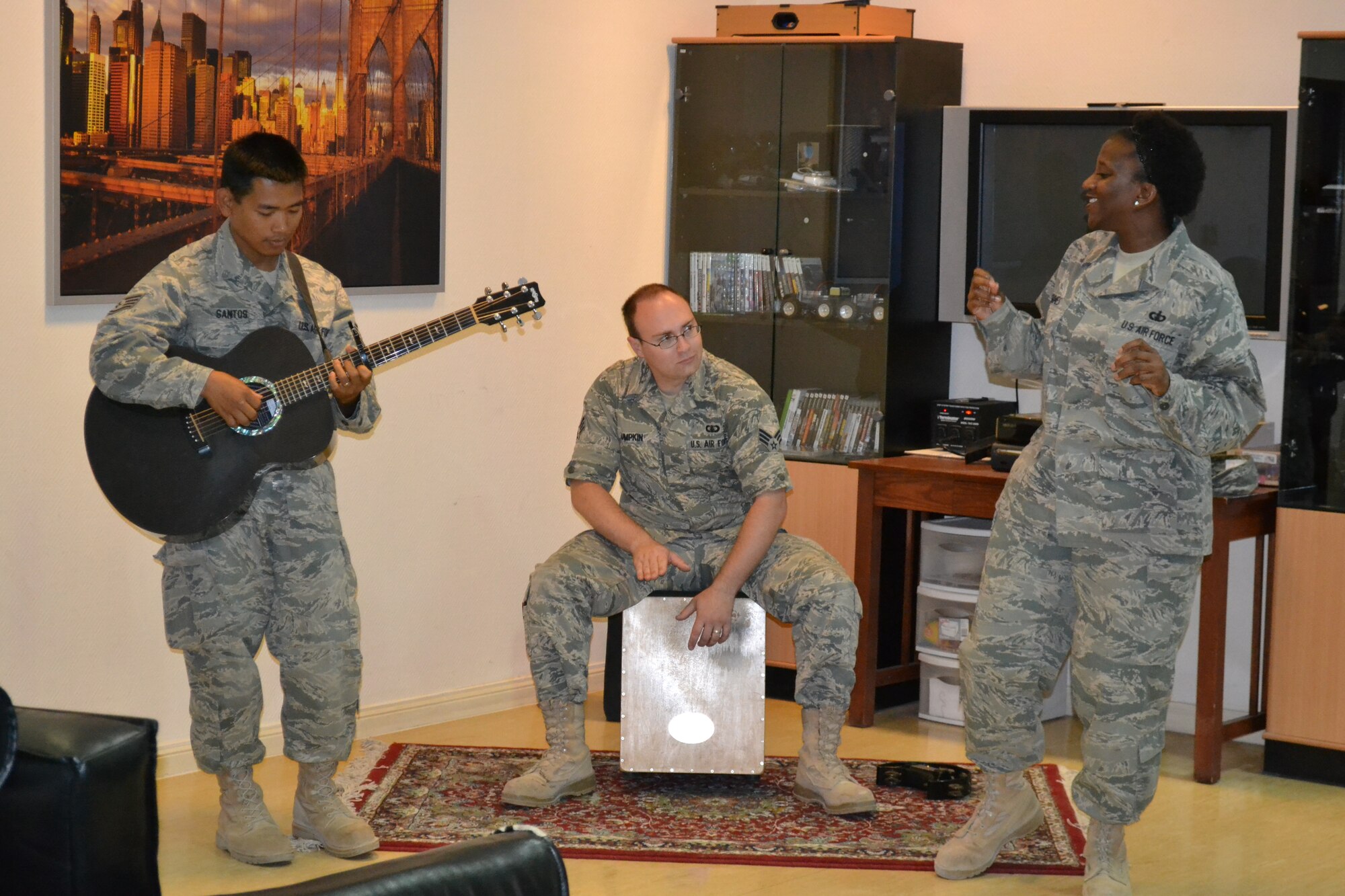 Members of “Hypersonic” assigned to U.S. Air Forces Central Command, perform for patients and staff at the Intra-Theater Care Program at Al Udeid Air Base, Qatar, Mar. 24, 2014.  The ITCP is the only recovery facility in the Central Command area of responsibility and wounded warriors from all services are sent here for treatment and recovery in order to return to their deployed location.   As members of the AFCENT band, this trio is an acoustic ensemble with voice, guitar, and cajon offering a wide variety of hit songs from genres such as jazz, pop, rock and country.   Staff Sgt. Daniel Santos on guitar and native of Bulacon, Philippines, Senior Airman Brian Lumpkin on cajon and a Seattle, Wash. native, and Technical Sgt. Amber Grimes, a vocalist from Columbus, Ga. are deployed from Yokota Air Base, Japan and are preparing to tour several bases throughout Afghanistan in April, along with the other band members. (U.S. Air Force Photo by Maj. Nicole David)