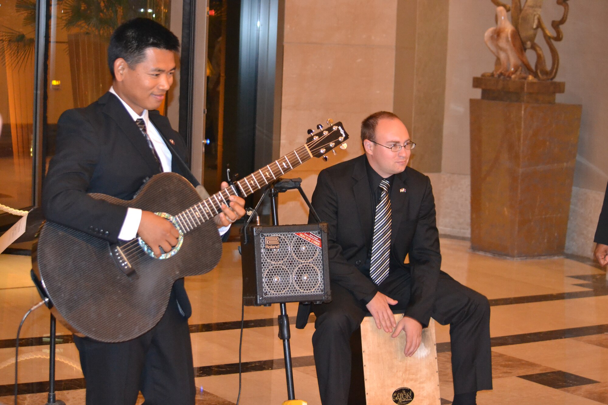 Members of “Hypersonic” assigned to U.S. Air Forces Central Command, perform at the St. Regis Hotel in downtown Doha, Qatar on Mar. 23, 2014.  As members of the AFCENT band, this trio is an acoustic ensemble with voice, guitar, and cajon and performed during the U.S. Embassy-Doha National Day celebration offering a wide variety of hit songs from genres such as jazz, pop, rock and country.   Senior Airman Brian Lumpkin on cajon and native of Seattle, Wash. and Staff Sgt. Daniel Santos on guitar and native of Bulacon, Philippines, are deployed from Yokota Air Base, Japan and are preparing to tour several bases throughout Afghanistan in April, along with the other band members.  (U.S. Air Force Photo by Maj. Nicole David)
