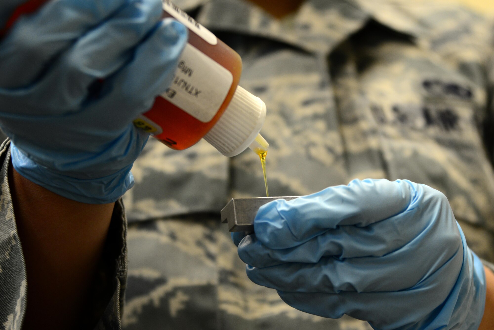 U.S. Air Force Senior Airman Janelle Benavidez, 35th Maintenance Squadron Nondestructive Inspection journeyman, fills a sample holder with oil standard to be tested as part of the Joint Oil Analysis Program at Misawa Air Base, Japan, March 11, 2014. The JOAP tests aircraft engine oils every 25 hours to assess metal levels. (U.S. Air Force photo/Senior Airman Derek VanHorn)