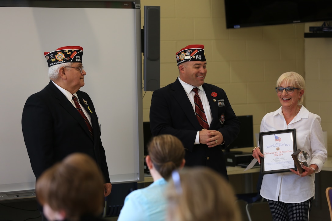 Members of the Veterans of Foreign Wars Post 9133 present Maria Cruz with the 2013 VFW National Citizenship Education Teacher Award, at Heroes Elementary School aboard Marine Corps Base Camp Lejeune, March 19. Cruz was recognized for hard work and dedication to her students and community. 