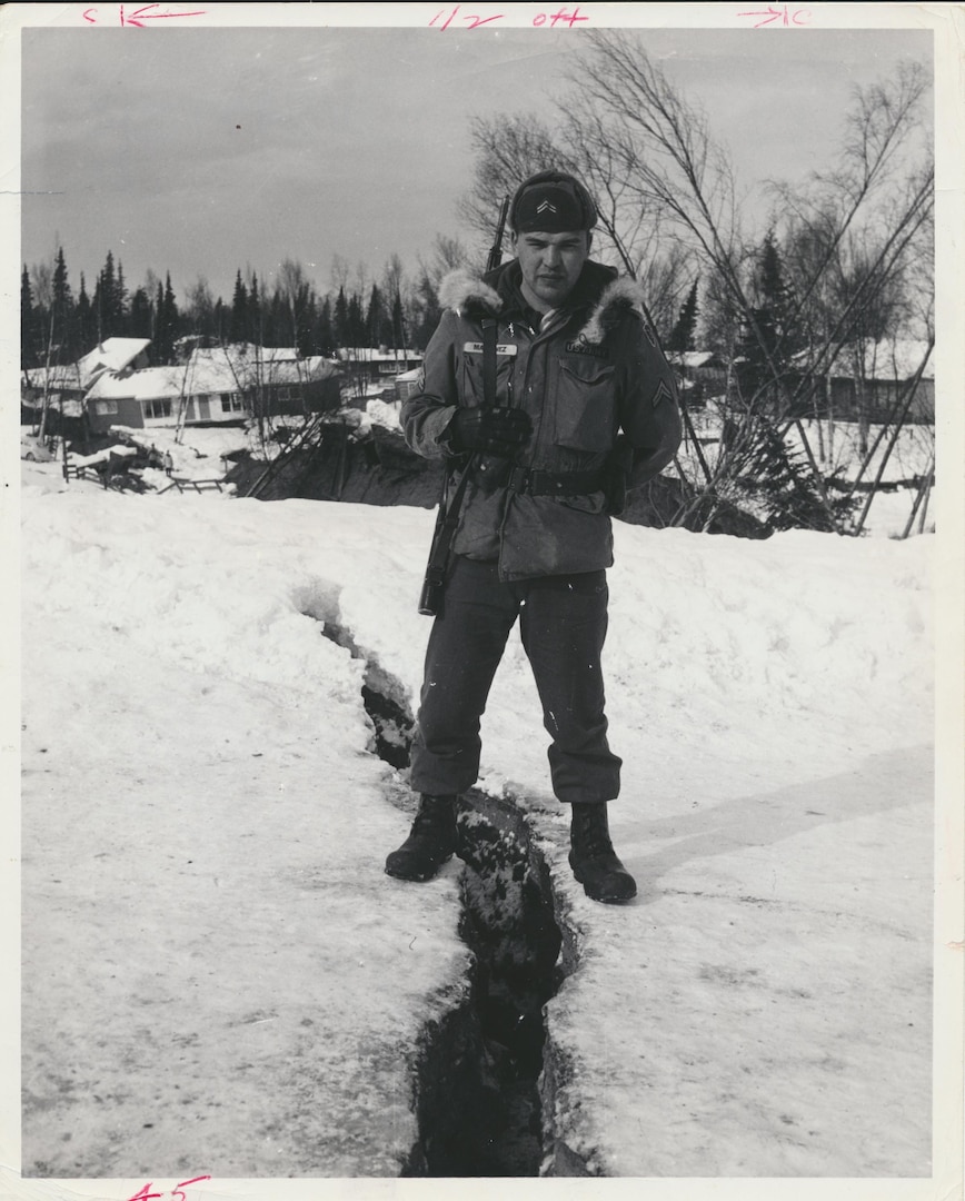 An Alaska National Guard member watches over a portion of the devastated Turnagain neighborhood of Anchorage on March 28, 1964, one day after the huge earthquake struck. The quake triggered the large fissure in the soil.