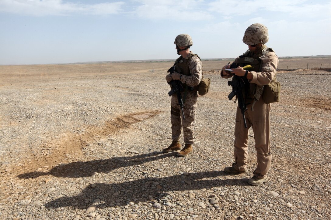 Captain Roger Collicott, right, helicopter landing zone manager with Marine Aircraft Group-Afghanistan, writes observation notes as Capt. Matt Blose, the safety officer with MAG-A, observes the helicopter landing zone during an HLZ study at Patrol Base Boldak, Helmand province, Afganistan, March 20, 2014.  Landing zone studies are performed as often as possible in order to update requirements and the coordination needed to maintain the HLZ, as well as to ensure proper procedures and safety requirements are set in place. (USMC Photo By: Sgt. Frances Johnson/Released)