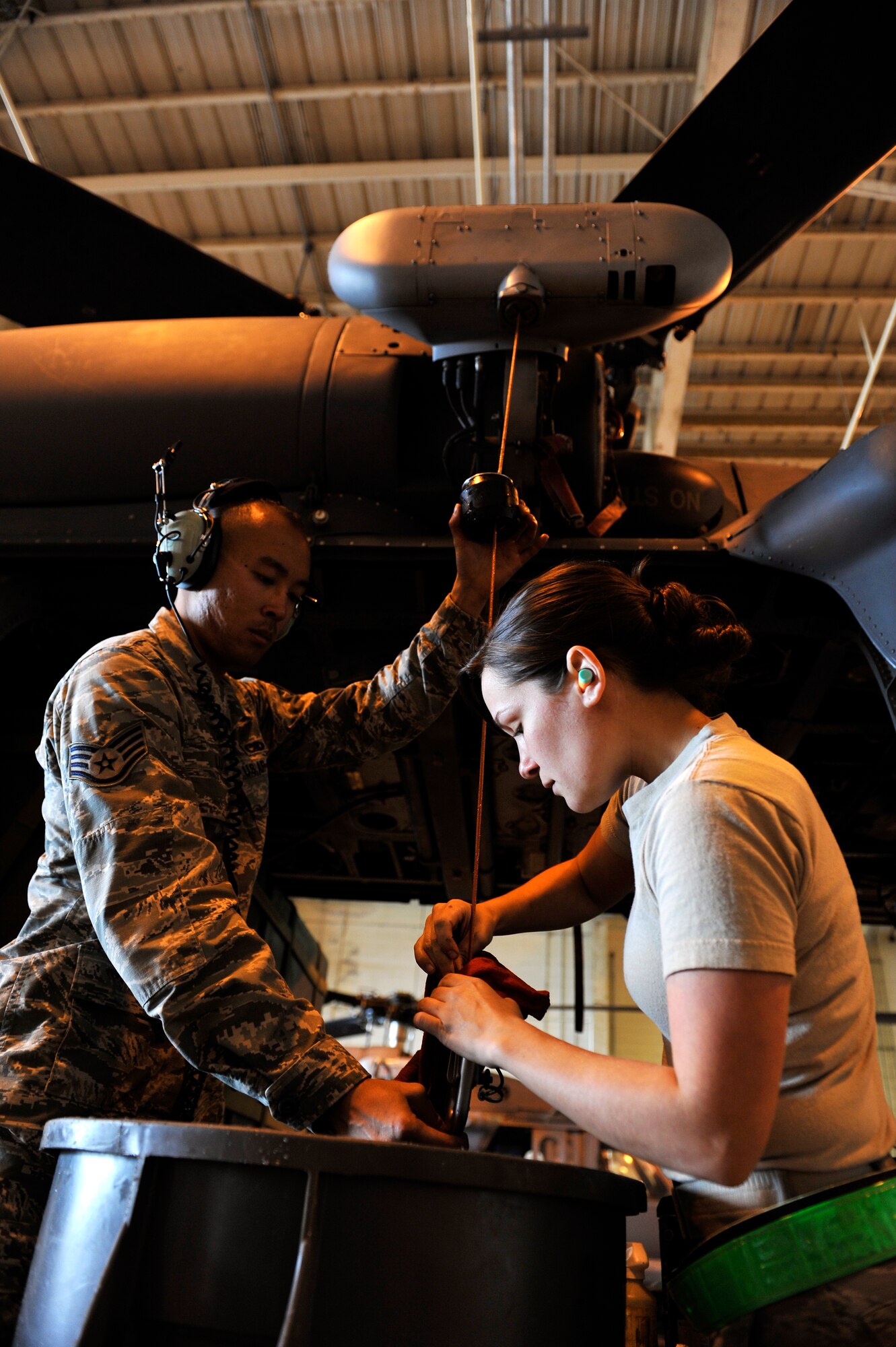 U.S. Air Force Staff Sgts. Robin Lu (left), and Erin Loporto (right), 33rd Helicopter Maintenance Unit crew chiefs, inspect the hydraulics of an HH-60G Pave Hawk helicopter during a scheduled inspection on Kadena Air Base, Japan, March 14, 2014. Maintenance and inspections are conducted before and after every mission to ensure aircraft safety and longevity. (U.S. Air Force photo by Naoto Anazawa)