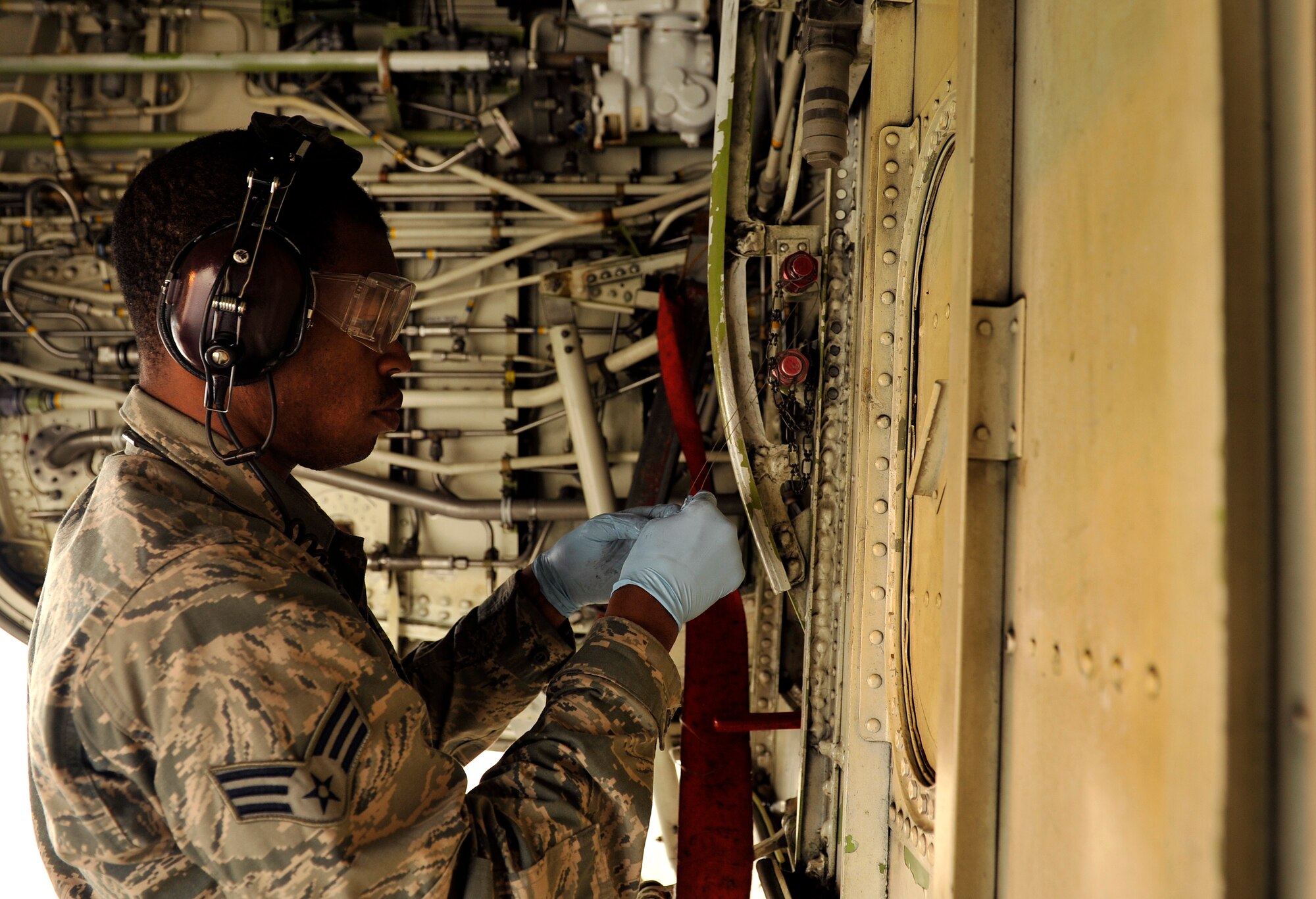 U.S. Air Force Senior Airman Maurice Johnson, 961st Aircraft Maintenance Unit crew chief, removes a safety pin from the engine of an E-3 Sentry Airborne Warning and Control System aircraft during routine maintenance on Kadena Air Base, Japan, March 14, 2014. Members of the 961st AMU inspect their aircraft daily to maintain standards and safety. (U.S. Air Force photo by Naoto Anazawa)