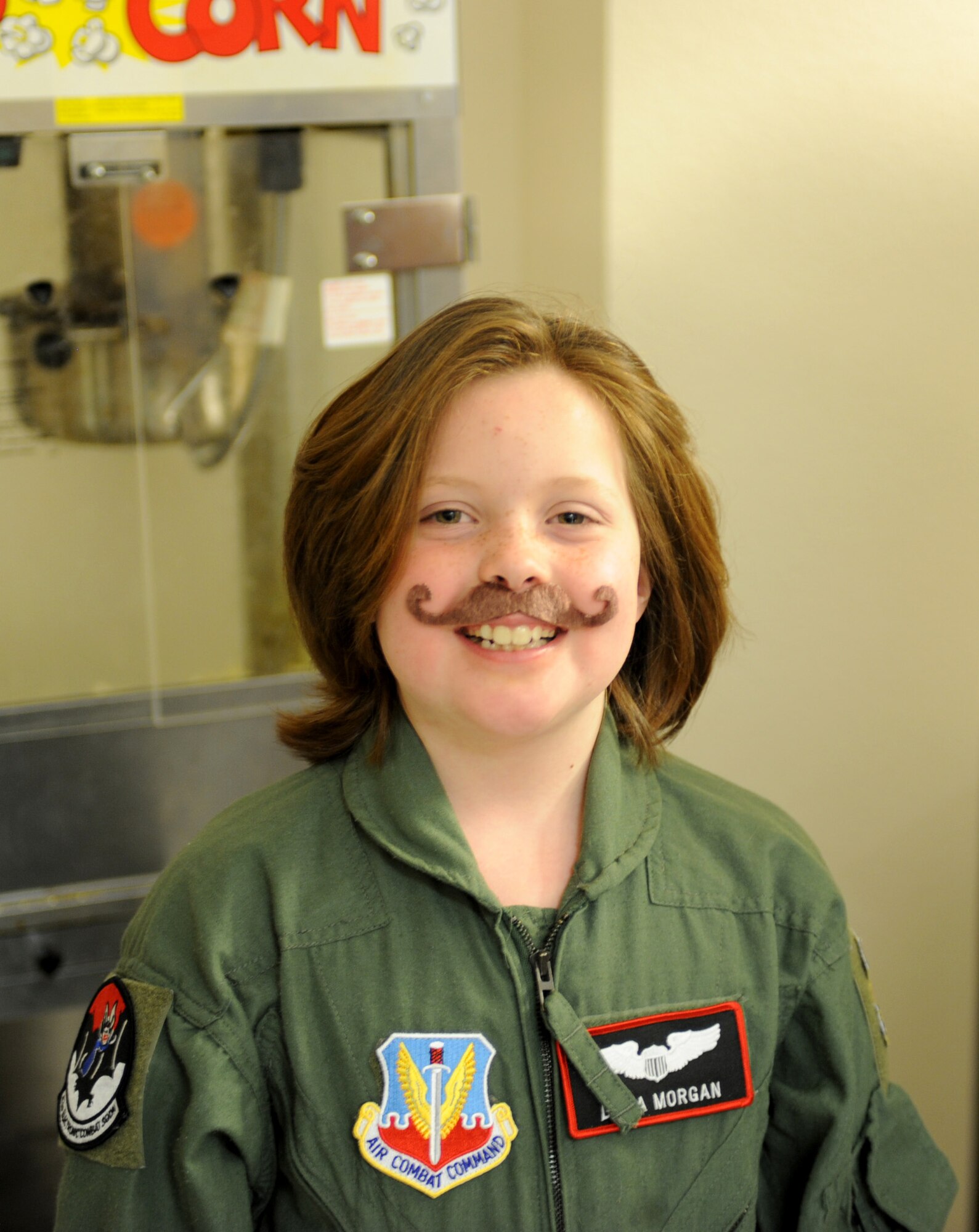 Dana Morgan, honorary Pilot for a Day, sports a fake mustache in recognition of “Mustache March” during her Pilot for a Day tour at Davis-Monthan Air Force Base, Ariz., March 14, 2014.  Each honorary pilot leaves D-M with patches, souvenirs and memories to help sustain them in the face of their personal challenges.  (U.S. Air Force Photo by Airman 1st Class Chris Massey/Released)