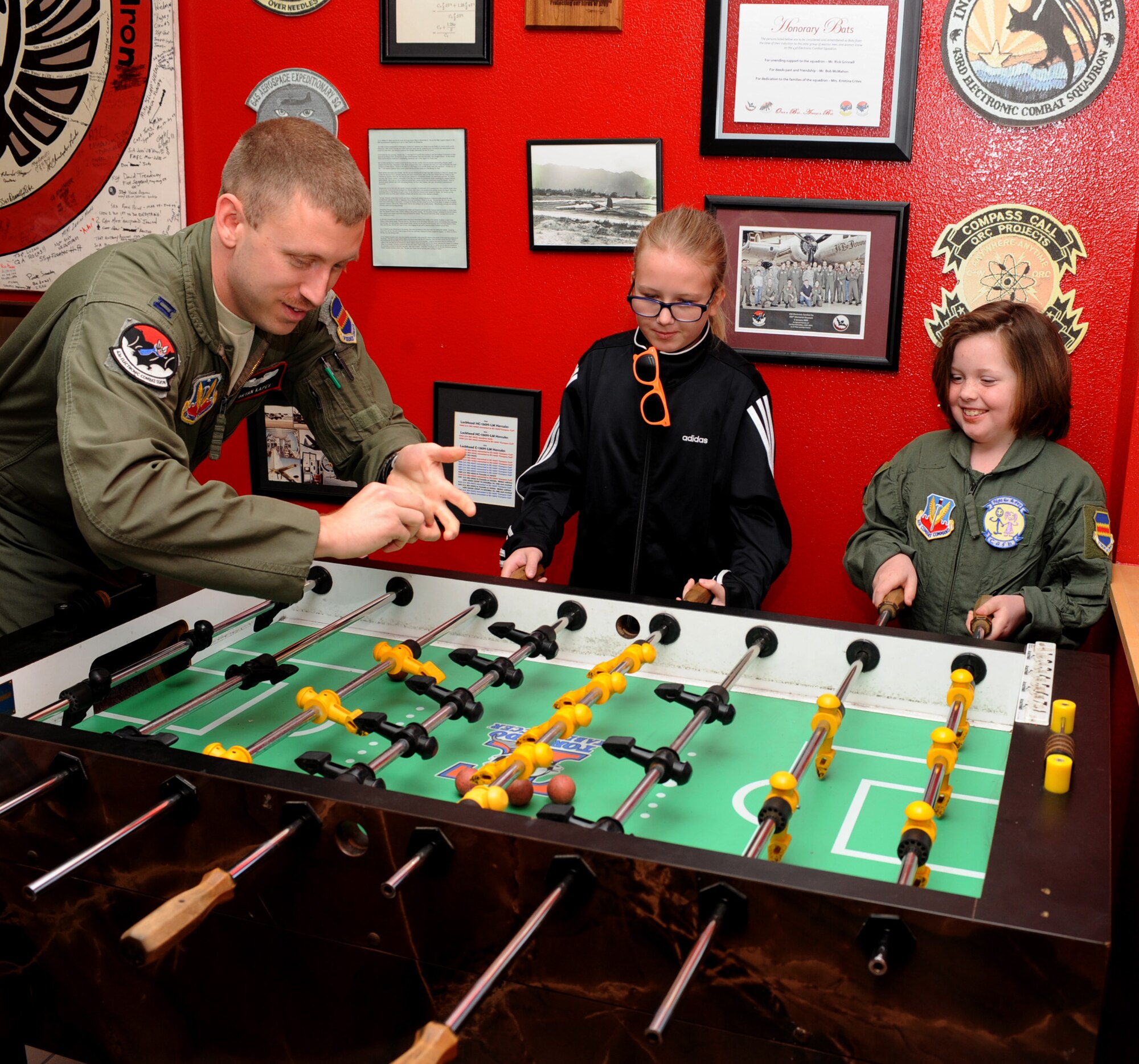 U.S. Air Force Capt. Bryan Kapes, 43rd Electronic Combat Squadron, Dana Morgan, honorary 43rd ECS Pilot for a Day, and Morgan's friend, Hope Smith, play foosball at Davis-Monthan Air Force Base, Ariz., March 14, 2014. Morgan and her family were escorted by Kapes, whose unit hosted the Pilot for a Day tour.  (U.S. Air Force Photo by Airman 1st Class Chris Massey/Released)