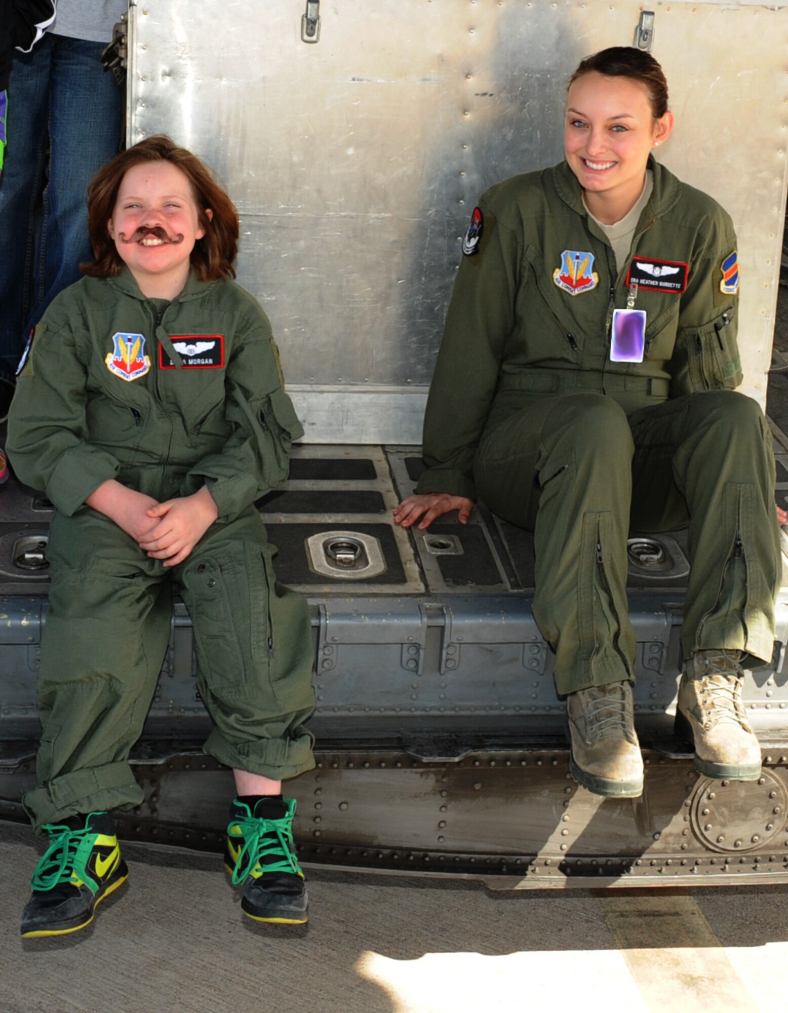 Dana Morgan, honorary Pilot for a Day, and U.S. Air Force Senior Airman Heather Burdette, 43rd Electronic Combat Squadron, sit on the back ramp of an EC-130H Compass Call during a Pilot for a Day tour at Davis-Monthan Air Force Base, Ariz., March 14, 2014.  Pilot for a Day is a program which allows children, who have serious or chronic conditions, and their families with the opportunity to be a guest of the 355th Fighter Wing and one of D-M's squadrons for the day.  (U.S. Air Force Photo by Airman 1st Class Chris Massey/Released)