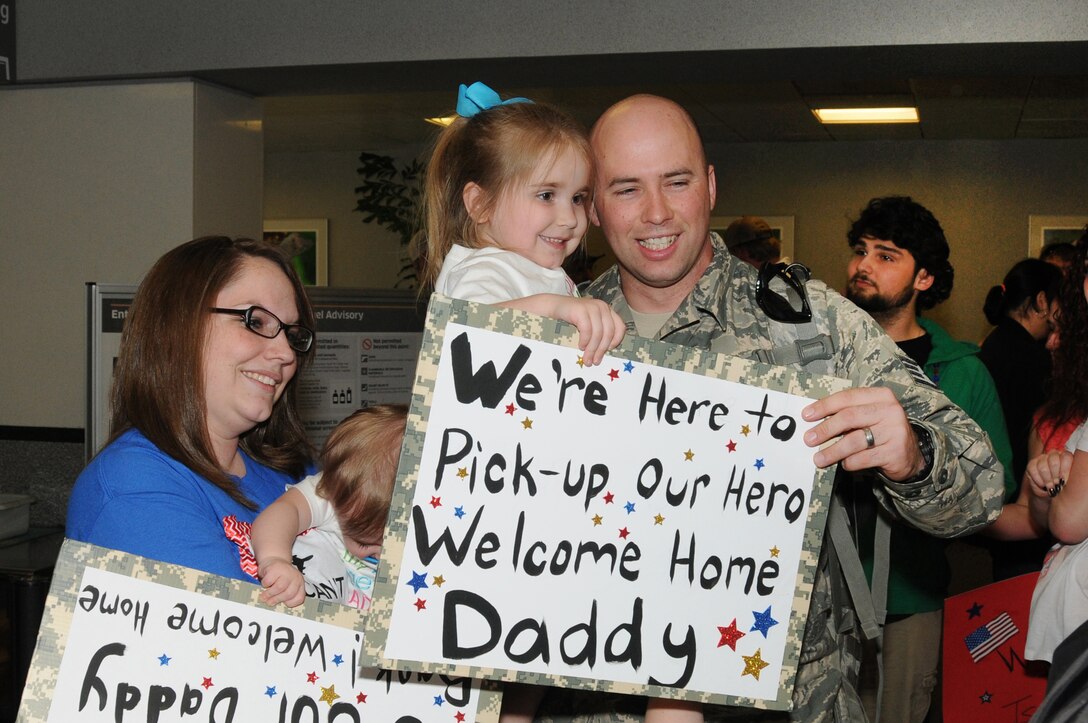 U.S. Air Force Staff Sgt. Joshua S. Peets  with the 186th Air Refueling Wing, Security Forces Squadron poses for a photo with his wife, Shawna, and children, Addyson and Paisley, at the Jackson-Evers International Airport, March 20, 2014, after a seven-month deployment to Southwest Asia.  (U. S. Air National Guard photo by Senior Master Sgt. Richard Davis/Released)