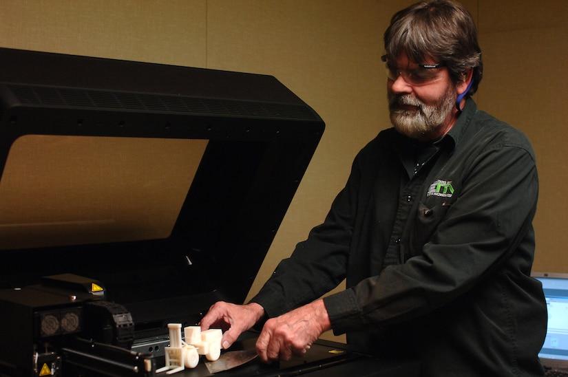 Gerald Collier, Enterprise Multimedia Center audiovisual specialist, removes a completed model project from a three-dimensional printer at Fort Eustis, Va., March 25, 2014.  The fabrication department of EMC can build products from the ground up, such as terrain models and large-format command boards by using computerized routers, plasma cutters, 3D printers and laser engravers. (U.S. Air Force photo by Senior Airman Teresa J.C. Aber/Released)