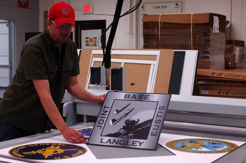 Kenneth Clevenger, Enterprise Multimedia Center digital imaging technician, removes printed unit logos from a cutter at Fort Eustis, Va., March 25, 2014. The EMC graphics department provides three-dimensional command shields, posters and displays with the ability to print on virtually any surface. (U.S. Air Force photo by Senior Airman Teresa J.C. Aber/Released)